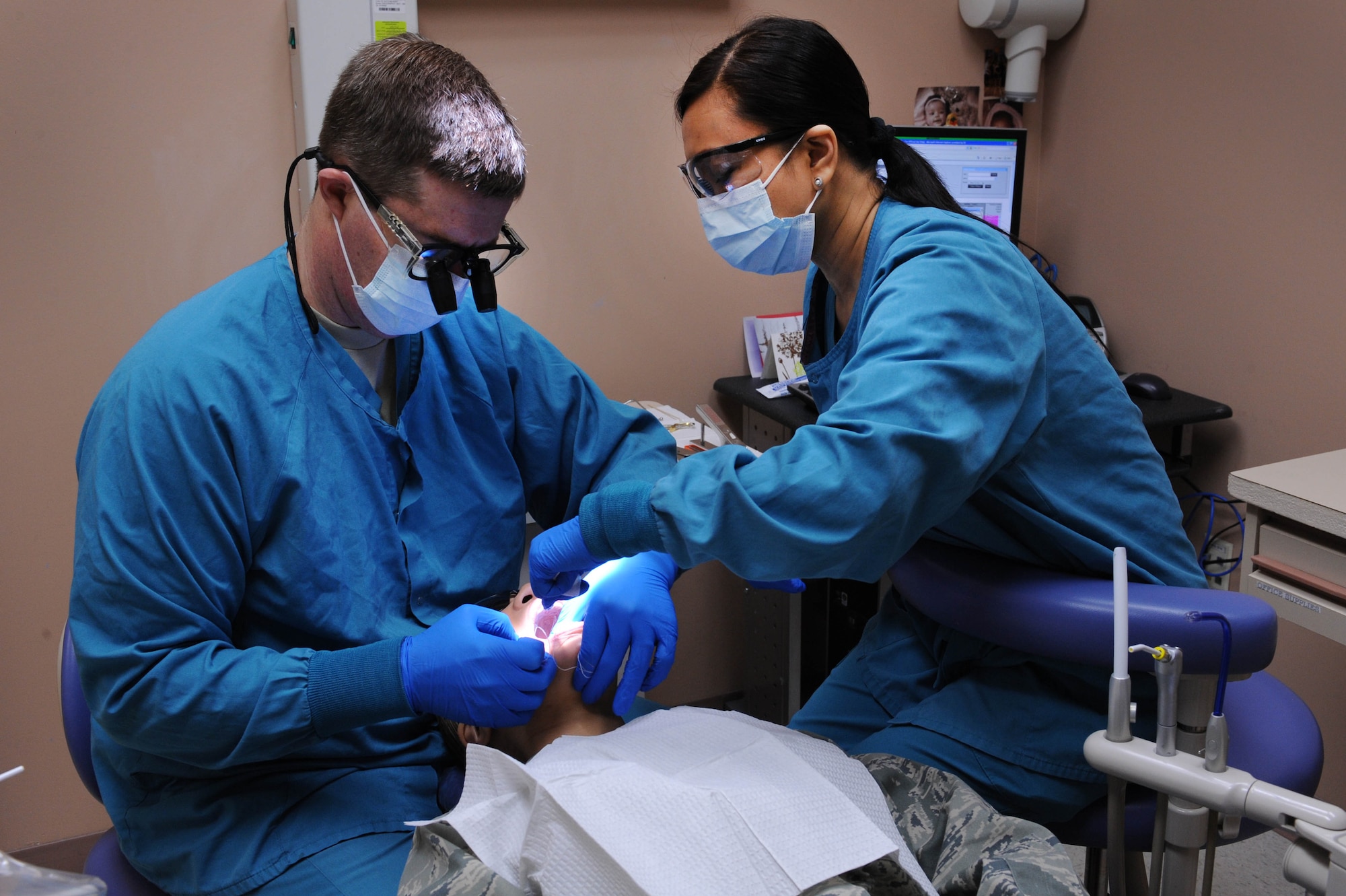NELLIS AIR FORCE BASE, Nev.-- (left to right)  Maj. Matthew Huffaker, 99th Dental Squadron, dentist, and Maria Pabala, a Red Cross dental assistant trainee, examine a patient at the Mike O'Callaghan Federal Hospital Dental Clinic Jan. 25. Ms. Pabala volunteers 40 hours a week during the six-month training to become a dentist assistant.  (U.S. Air Force photo by Airman 1st Class Matthew Lancaster)



