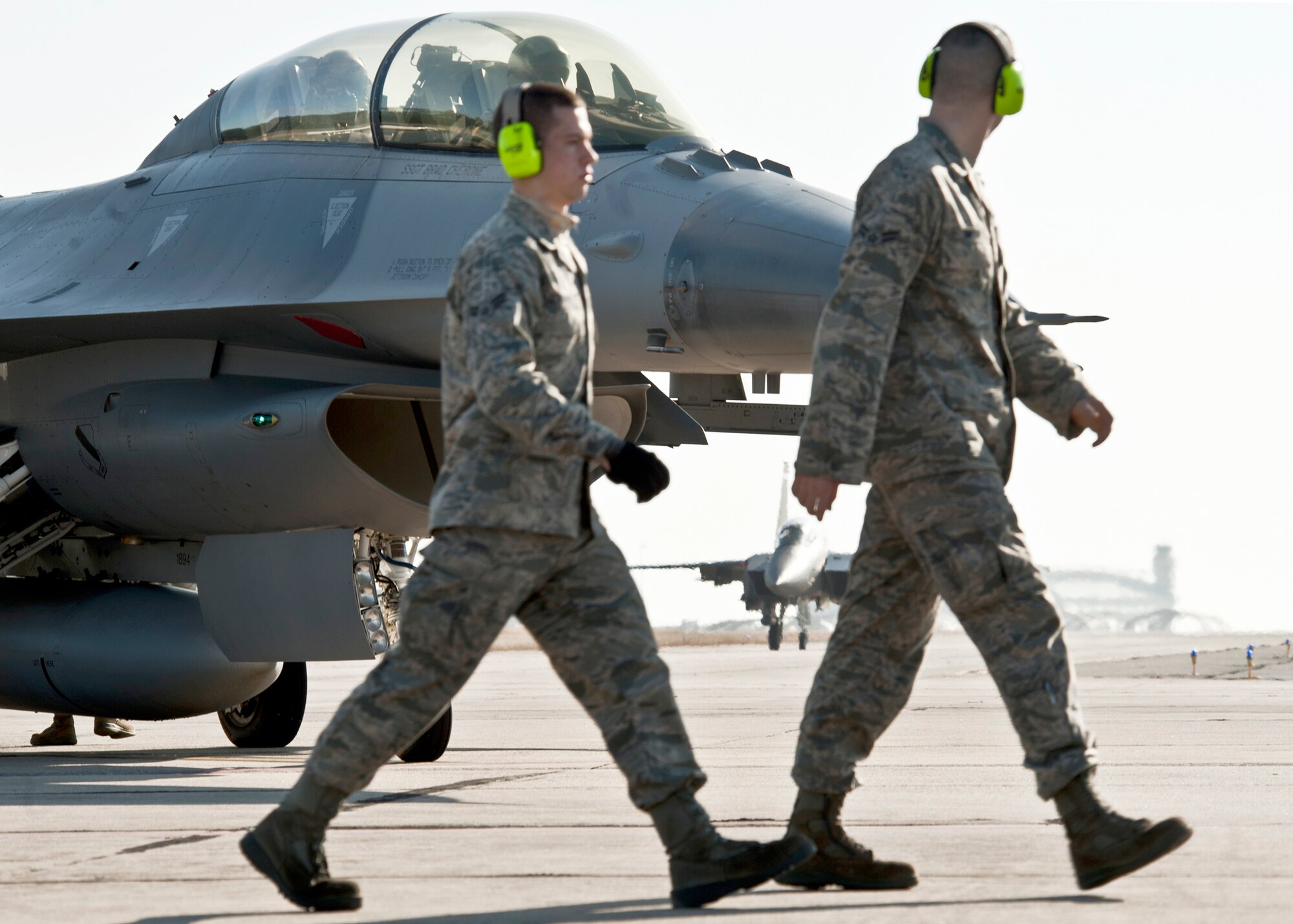 F-15E Strike Eagle maintainers walk past a parked F-16 Fighting Falcon to move into place as their aircraft taxis toward them for a final check before takeoff Jan. 18, 2011, from Eglin Air Force Base, Fla. This F-15E is equipped with the new APG-82 radar, which replaces the 24-year-old APG-70 radar system. Maintainers are assigned to the 46th Maintenance Group. (U.S. Air Force photo/Samuel King Jr.)
