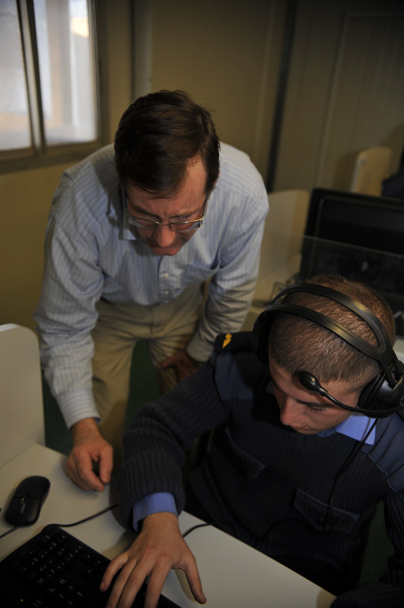 Robert Loebe, Iraqi Air Force College English language trainer, gives directions to an Iraqi cadet pilot inside the new American Language Course computer lab, Jan. 20. With assistance from the Defense Language Institute, English Language Center, San Antonio, Texas, the military academy located in Tikrit, Iraq, opened a computer lab as part of its extensive English language training program. Mr. Loebe taught the first lessons to the students out of the modern $130,000 facility. (U.S. Air Force photo by Senior Master Sgt. Larry Schneck/Released)