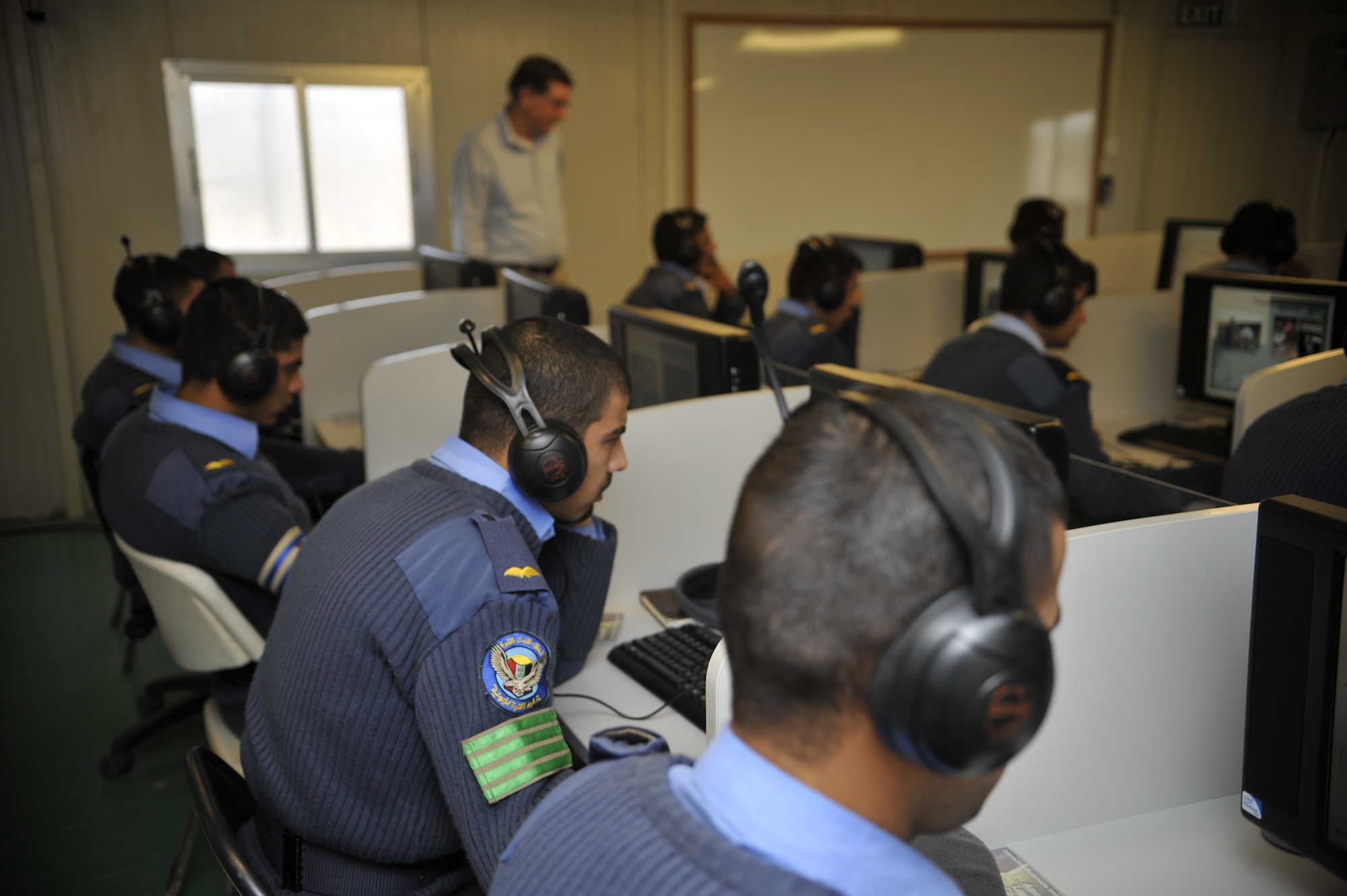 Robert Loebe, Iraqi Air Force College English language trainer, assists a group of cadet pilots in Class 76 inside the new American Language Course computer lab, Jan. 20. With assistance from the Defense Language Institute, English Language Center, San Antonio, Texas, the military academy located in Tikrit, Iraq, opened a computer lab as part of its extensive English language training program. Mr. Loebe taught the first lessons to the students out of the modern $130,000 facility. (U.S. Air Force photo by Senior Master Sgt. Larry Schneck/Released)