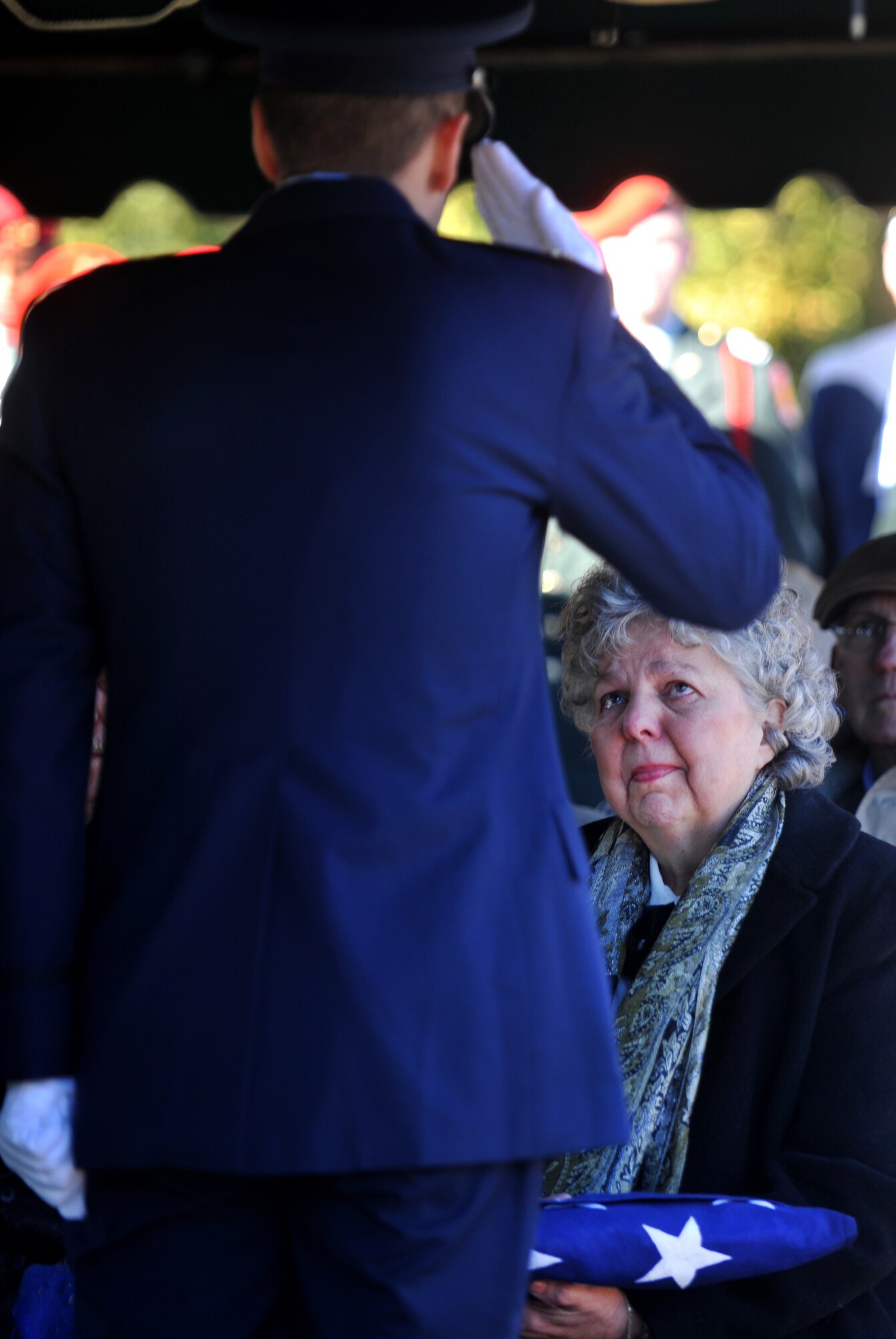 OZARK, Ala.-- Linda Dees, niece of 1st Lt. Robert Franklin Dees, looks to the Airmen from Eglin Air Force Base Honor Guard rendering a salute to the flag in honor of her uncle during his memorial service Jan. 22. The aircraft of Lieutenant Dees, a F-84E Thunderjet pilot,  was shot down over North Korea in 1952 during a combat mission. (U.S. Air Force photo/Airman 1st Class Joshua Green)(RELEASED)
