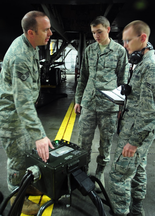 (Left to right) Staff Sgt. Chris Dieball, 28th Aircraft Maintenance Squadron crew chief instructor, explains the process of using a spider generator connector to run the electronic components on the B-1B Lancer during maintenance to Airman Mark Vadnais and Airman 1st Class Christian Mains, 28th AMXS able chiefs, at Ellsworth Air Force Base, S.D., Jan. 21.  When Airmen conduct maintenance on the B-1, the plane is hooked up to and runs off of a generator to prevent wearing out the battery. (U.S. Air Force photo/Senior Airman Anthony Sanchelli)