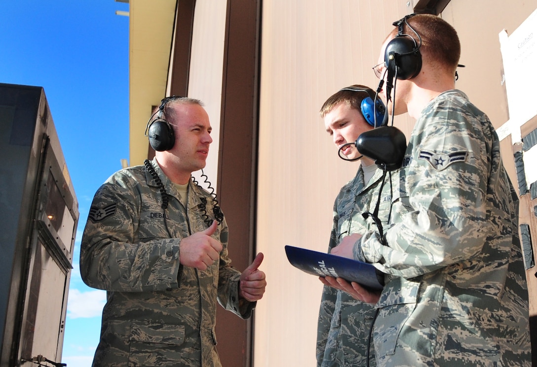 (Left to right) Staff Sgt. Chris Dieball, 28th Aircraft Maintenance Squadron crew chief instructor, explains the process of using a diesel generator to run the electronic components on the B-1B Lancer during maintenance to Airman Mark Vadnais and Airman 1st Class Christian Mains, 28th AMXS able chiefs, at Ellsworth Air Force Base, S.D., Jan. 21.  When Airmen conduct maintenance on the B-1, the plane is hooked up to and runs off of a generator so as not to wear out the battery. (U.S. Air Force photo/Senior Airman Anthony Sanchelli)