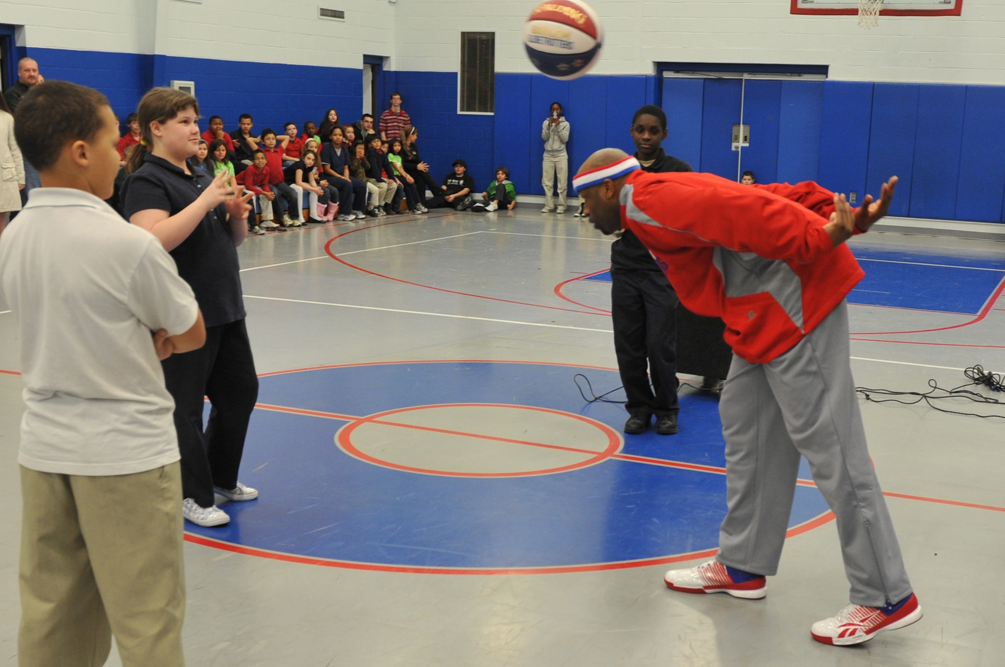 Aundre “Hot Shot” Branch of the Harlem Globetrotters demonstrates a basketball trick to the kid’s youth center kids, at Little Rock Air Force Base, Ark., Jan. 21, 2011. As a Harlem Globetrotter one of Hot Shot’s responsibilities is to reach out to the fans, and talked to them about what it takes to be a Harlem Globetrotter. (U.S. Air Force photo by Airman 1st Class Rusty Frank)