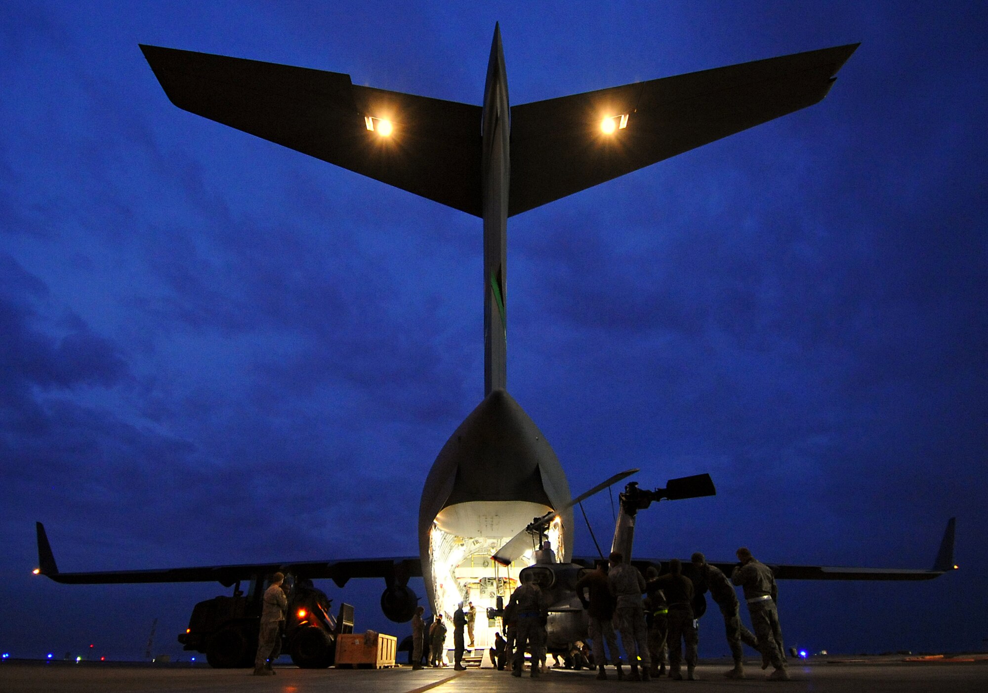 Airmen, Marines and Sailors work together to load an AH-1 Whiskey Super Cobra on a C-17 Globemaster III well into the morning hours. Airmen with the 386th Expeditionary Readiness Squadron and loadmasters with the 817th Expedtionary Airlift Squadron worked with Marines and Sailors of the 26th Marine Expeditionary Unit recently to get their cargo to a forward location. (U.S. Air Force photo by Senior Airman Cynthia Spalding)