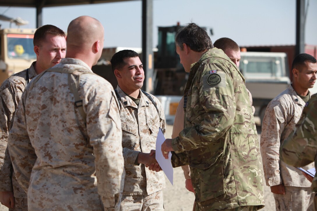 U.K. Royal Air Force Group Captain Guy van den Berg, the commanding officer of the 903rd Expeditionary Air Wing and airfield manager, congratulates Staff Sgt. Uriah Gruber, the training chief for the Aircraft Rescue and Firefighting section of Marine Wing Support Squadron 373, 3rd Marine Aircraft Wing (Forward), during an awards ceremony aboard Camp Bastion, Afghanistan, Jan. 25.  U.K. service members and Marines from the ARFF received letters of appreciation for their superior service while working in a joint environment aboard Camp Bastion.