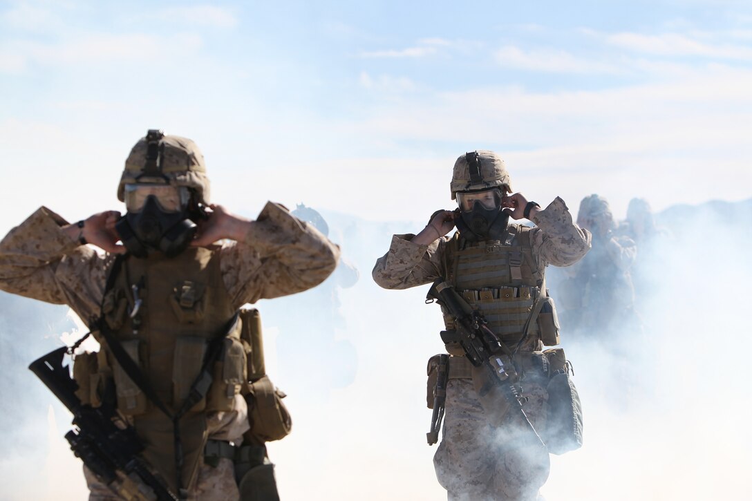 Marines and sailors with Company E., 2nd Battalion, 7th Marine Regiment, break the seals on their M50 Gas Masks in a cloud of CS gas during an outdoor gas exercise performed at range 210 Jan. 26, 2011. The Marines and sailors in full protective gear take turns marching through the cloud of gas to test and become acquainted with their new gear.