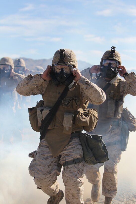 Marines and sailors with Company E., 2nd Battalion, 7th Marine Regiment, break the seals on their M50 Gas Masks during an outdoor gas exercise performed at range 210 Jan. 26, 2011. The Marines and sailors in full protective gear take turns marching through the cloud of gas to test and become acquainted with their new gear.