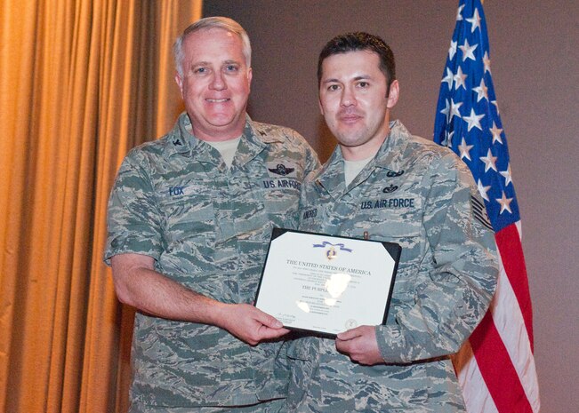 NELLIS AIR FORCE BASE, Nev.-- Col. Kevin Fox, 99th Mission Support Group commander, presents the Purple Heart to Tech. Sgt. Jermaine Kindred, 99th Civil Engineer Squadron explosive ordnance disposal technician, for his honorable service during Operation Enduring Freedom. Sergeant Kindred sustained injuries from an improvised explosive device detonation in Kandahar, Afghanistan, in September. The Purple Heart is awarded to members of the U.S. military who are wounded by an enemy during combat operations. (U.S. Air Force photo by Airman 1st Class Jamie Nicley)