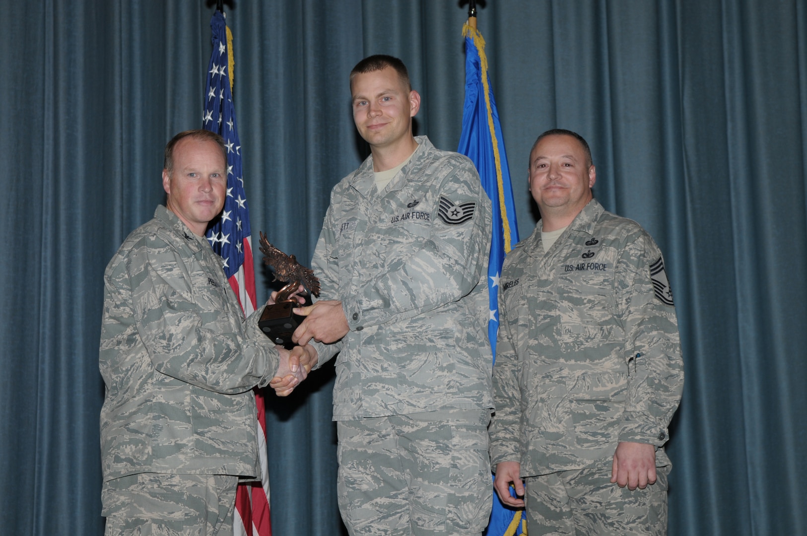 Col. Scott Peel, 902nd Mission Support Group commander, and Chief Master Sgt. Jesus Mireles III, 902nd MSG superintendent, present Tech. Sgt. Robert Bartlett, Air Force Personnel Center, with the award for the Honor Guard Member of the Year, NCO category, during the Joint Base San Antonio Randolph 4th Quarter Award Ceremony at Randolph Air Force Base, Texas, Jan. 26. (U.S. Air Force photo/Joel Martinez)