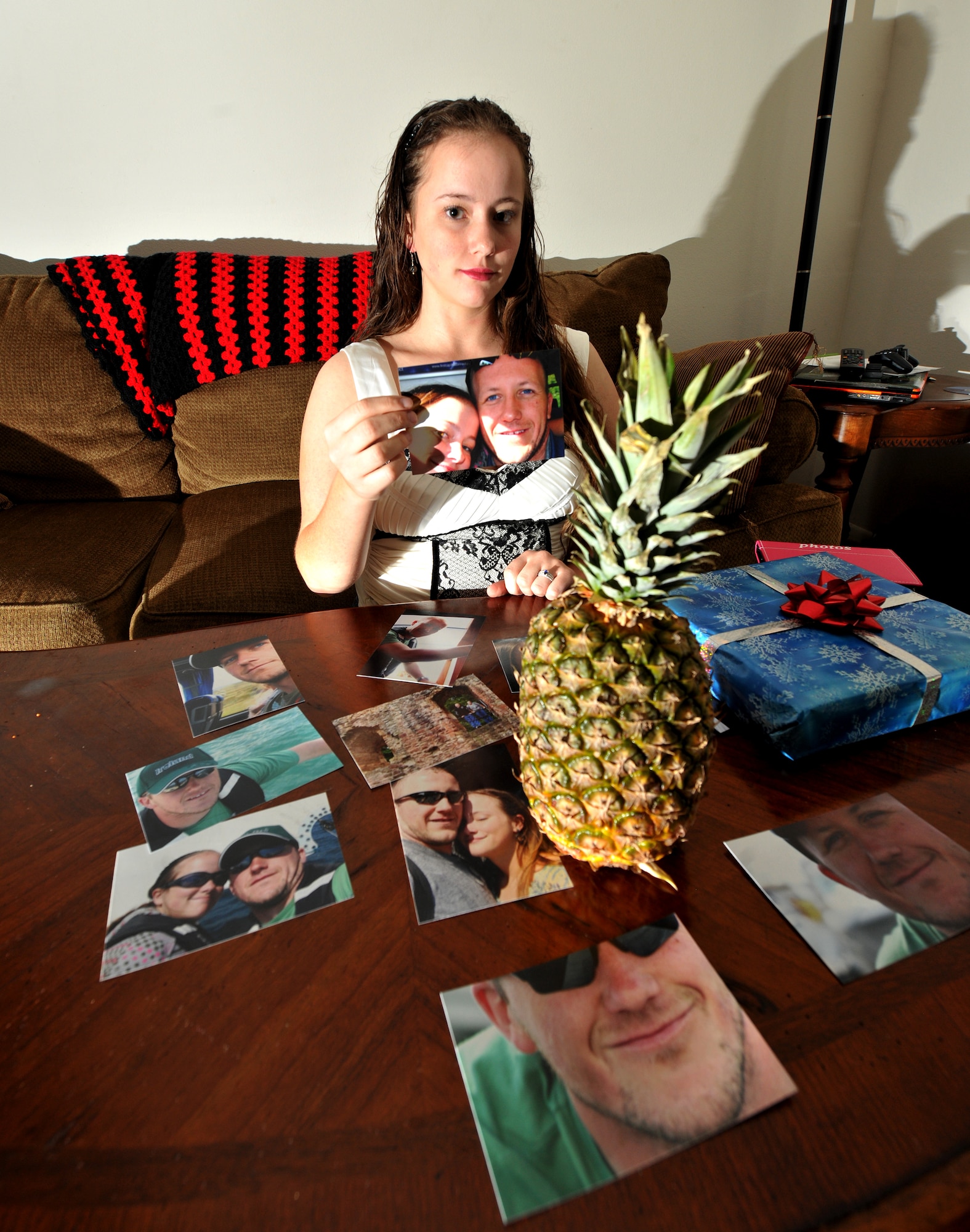 MOODY AIR FORCE BASE, Ga.-- A pineapple sits on a table surrounded by pictures and a Christmas present during a portrait of Airman 1st Class Brigitte Brantley-Sisk, 23rd Wing Public Affairs journalist, Jan. 12. Her husband told her in his deployed location there wasn’t any pineapples so she bought him one for his homecoming and a present because he missed Christmas. (U.S. Air Force photo/Airman 1st Class Joshua Green)(RELEASED)
