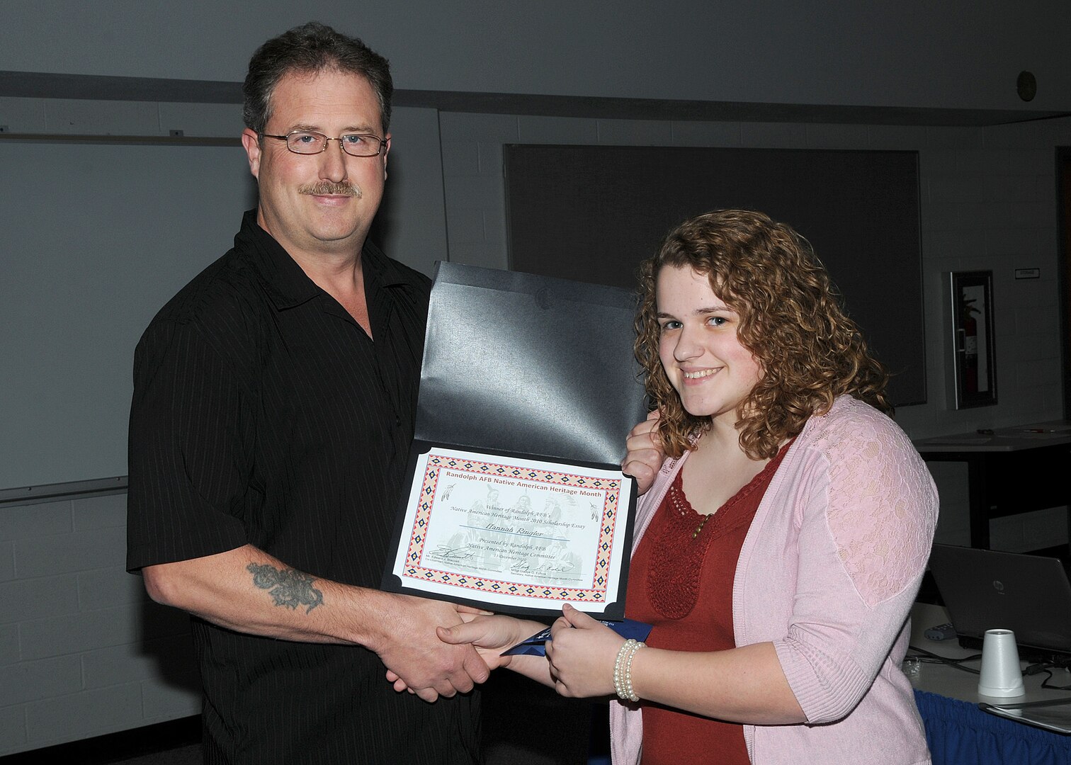 Hannah Ringler, the winner of the Native American Heritage Month 2010 scholarship, receives a certificate and check from Edward J. Blauvelt, a Training Specialist-Registrar/Security Manager with 12 Operation Support Squadron. Ringler, a senior at Randolph High School, wrote an essay on the importance of Native American Heritage in a military institution. She is the daughter of Senior Master Sgt Gordon and Lisa Ringler. He is with the 313 FLTF at Kelly Air Force Base.
(U.S. Air Force photo/David Terry)