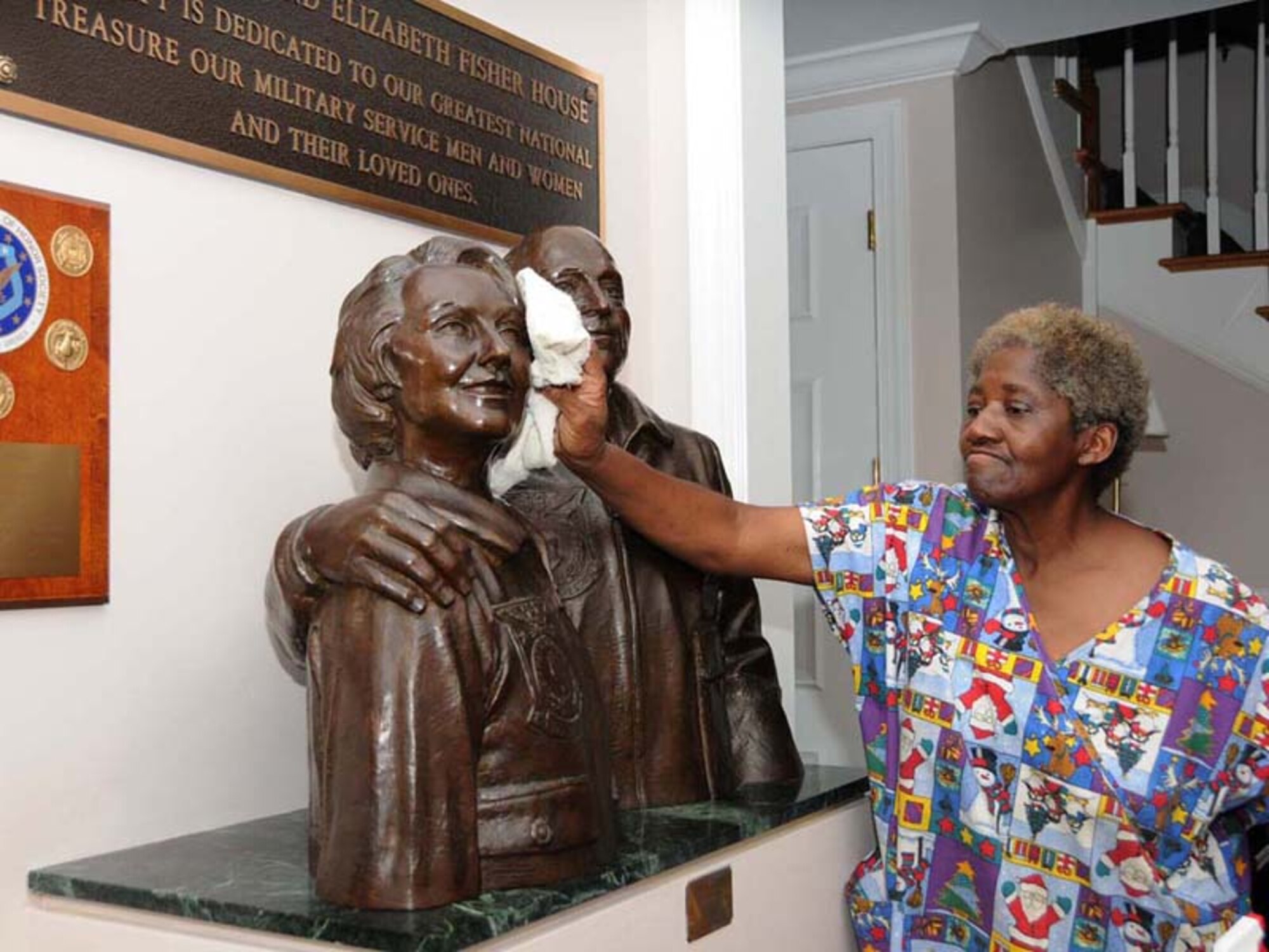 Mary Burley, housekeeper at Keesler’s Fisher House, polishes a bronze statue of Zachary and Elizabeth Fisher, founders of the Fisher House program. By the time Zachary Fisher died in 1999, he and his wife had financed more than 20 Fisher Houses. (U.S. Air Force photo by Kemberly Groue)