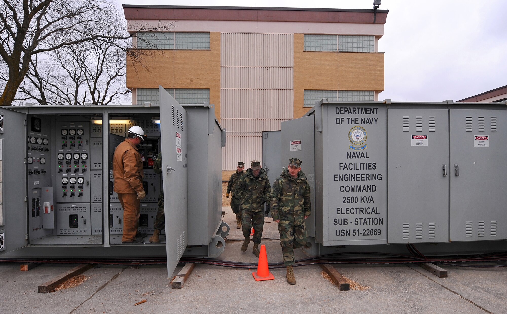 OFFUTT AIR FORCE BASE -- (From front to back) Navy Petty Officer 1st Class Timothy Duvall, construction electrician, Navy Petty Officer 1st Class Mike Kain, utilitiesman, and Navy Petty Officer 1st Class Jonathan Johnson, construction mechanic, walk between two 2,500 KVA electrical substations outside the headquarters of U.S. Strategic Command here as Navy Petty Officer 1st Class Adam Binon, lead electrician, instructs Todd Osgood, 55th Civil Engineer Squadron, on how to operate the relay protection for the circuit breaker on the left. The Sailors are part of a Mobile Utilities Support Equipment team out of Port Hueneme, Calif., that were here recently to install two substations for the building after a water main broke outside the facility Dec. 20, which caused electrical issues after water flooded the boiler room. U.S. Air Force photo by Josh Plueger (released)