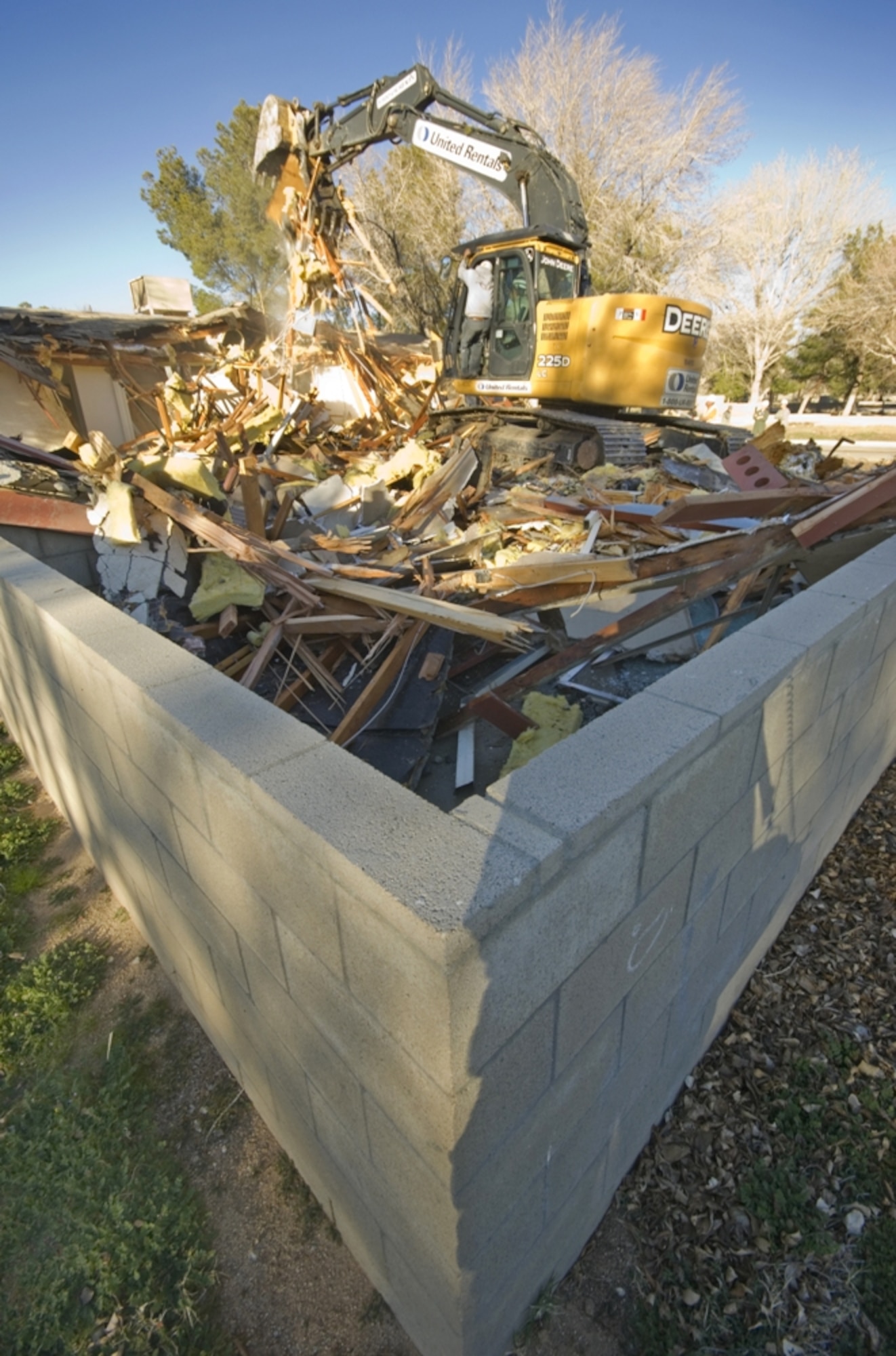 Brig. Gen. Robert C. Nolan II, Air Force Flight Test Center commander, operates the bulldozer used to take down the first house of a housing demolition project that started Jan. 21. The project will remove Unaccompanied Officers Quarters and Unaccompanied Noncommissioned Officers Quarters leaving the Temporary Lodging Facilities as the only pre-1999 houses still standing. Over the next six to nine months the TLFs will be moved to Joshua Acres, clearing the way for the current TLFs’ demolition. (Air Force Photo by Rob Densmore)