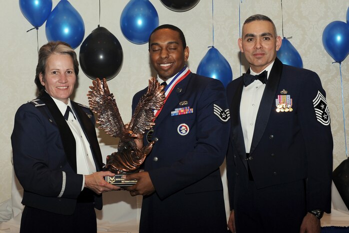 Col. Martha Meeker, left, and Chief Master Sgt. Jose LugoSantiago, right, presents Staff Sgt. Derrick Gonzales with the Honor Guard Manager of the Year award for 2010 during the annual awards banquet held at the Charleston Club Jan 20, 2010. Airmen, Sailors and civilians were presented with an award for their outstanding accomplishments from one of the 15 different categories recognized. Unable to attend the banquet due to deployment or other reasons was, from the 628th Mission Support Group, Noncommissioned Officer of the Year Staff Sgt. Akeem Parks; from the 628 MSG, Senior Noncommissioned Officer of the Year Master Sgt. Michael Patterson; from the 628 MSG, First Sergeant of the Year Master Sgt. Steven Hart; and from the Naval Weapons Station, Sailor of the Year Personnel Specialist 1st  Class Petty Officer James Long. Colonel Meeker is the Joint Base Charleston commander, Chief LugoSantiago is the 628th Air Base Wing command chief and Sergeant Gonzales is from the 628th Force Support Squadron. (U.S. Air Force photo/Tech. Sgt. Chrissy Best)