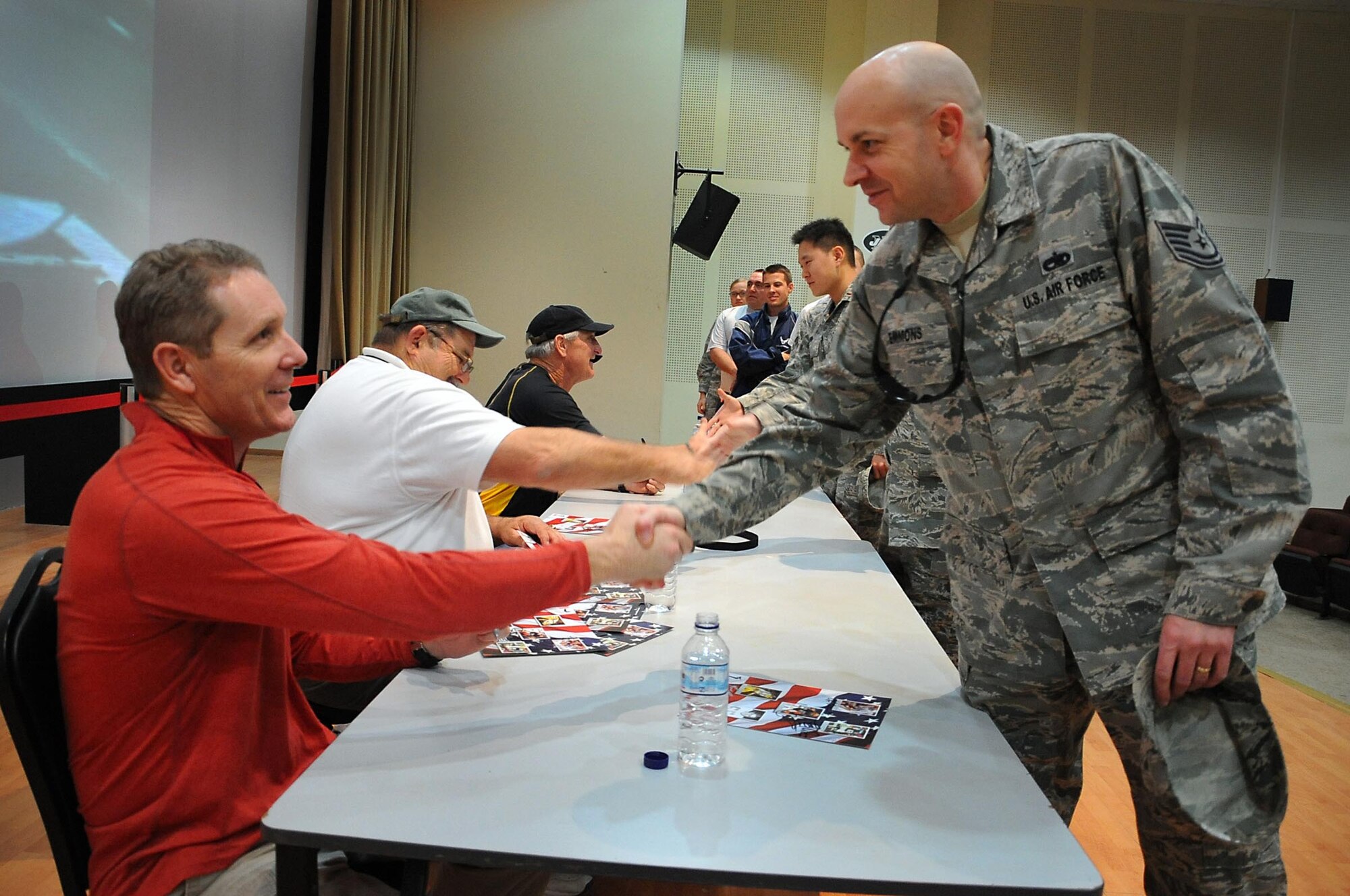 Tech. Sgt. William Emmons, 386th Air Expedtionary Wing weapons safety manager, shakes NFL Alumni Ken Greene's hand during an autograph signing Jan. 25. Armed Forces Entertainment presented NFL Alumni legends Lyle Blackwood, Ed White, Ron Pritchard, Ken Greene and Ray Carolin for a meet and greet with military members deployed here. (U.S. Air Force photo by Senior Airman Cynthia Spalding)