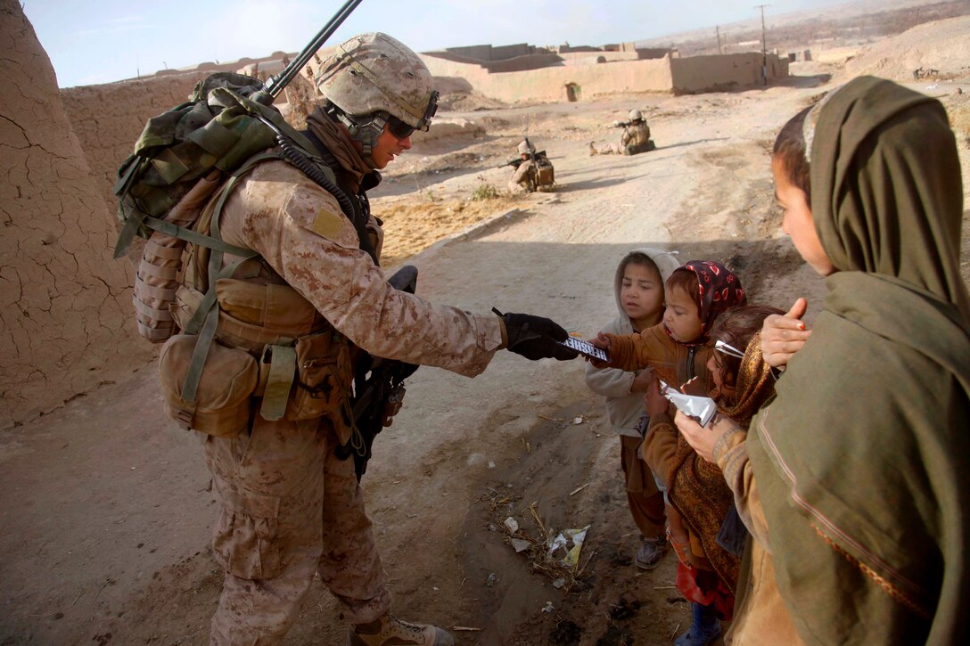 U.S. Marine Corps Sgt. Frank Denault hands candy to Afghan children during a census patrol in the Sangin district of Helmand province, Afghanistan, Jan. 17, 2011. Denault is assigned to Lima Company, 3rd Battalion, 5th Marine Regiment, Regimental Combat Team 2.