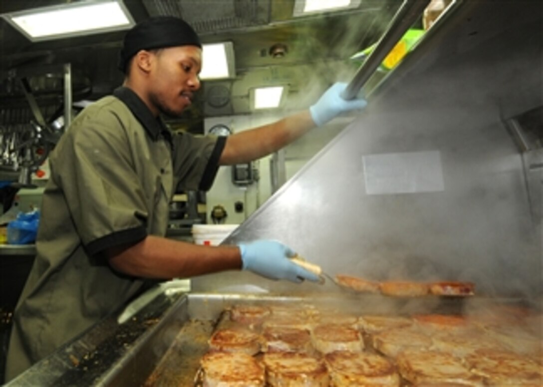Seaman Diante A. Johnson prepares pork chops in the ship's galley for the crew aboard the guided-missile cruiser USS Anzio (CG 68) underway in the Pacific Ocean on Jan. 24, 2011.  