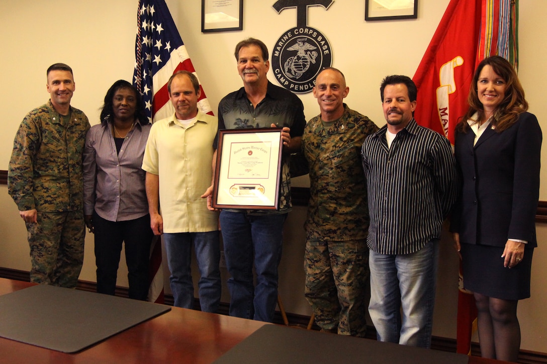 (From left to right) Lt. Col. Todd Kerzie, Facilities Maintenance Officer; Ruby Reed, Quality Assurance Specialist; Jason Estensen, Maintaince Control; Rick Monroe, General Support Shop Supervisor; Col. Nicholas F. Marano, commanding officer, Marine Corps Base Camp Pendleton; Anthony DeJohn, program analysis; Susan Stuffle, Continuous Process Improvement manager, Headquarters Marine Corps, Installations and Logistics department; (not pictured) Anthony Reyes, president, National Federation of Federal Employees, Local 919; receive a CPI award for Project Excellence at Building 1160, Jan.26. The CPI awards recognize noteworthy achievements by organizations and individuals throughout the Marine Corps and are designed to continually improve the speed, quality and affordability of supporting processes to meet those requirements. To meet the high demand for their workload, Facilities Maintenance Department’s General Support team developed a project to reduce annual costs by $9.2 million with potential future annual savings of $10-15 million.