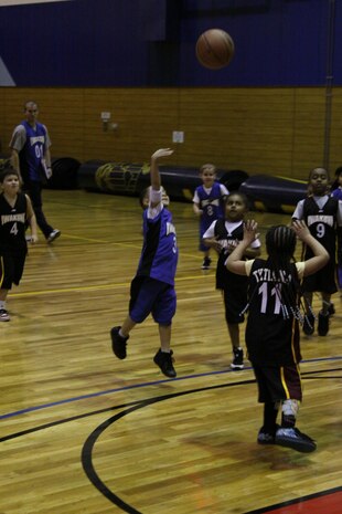 Ronald Pearcy, Blue Bolts power forward, launches the ball over the heads of Tytiana McCourt, Heat point guard, and her teammates during the Blue Bolts vs. Heat game in the 5- to 6-year-old division at the IronWorks Gym Sports Courts here Jan. 27.