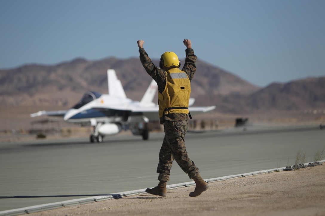 Lance Cpl. Danial Farias, an expeditionary airfield systems technician with Marine Wing Support Squadron 374, sends various signals to a NASA F/A-18 pilot, who landed in support of the squadron’s arrestment training Jan. 27, 2011.