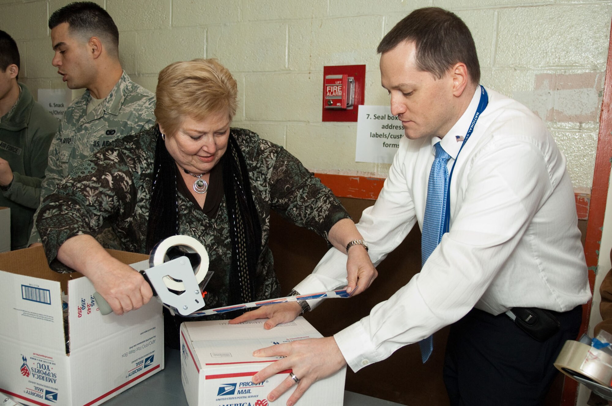 HANSCOM AIR FORCE BASE, Mass. – Gail Zaslow (left) and John Gould seal boxes at the end of assembly line during the Troop Care Drive on Jan. 20. Hanscom’s Company Grade Officers Council sponsored and organized the event, held in Building 1105A. (U.S. Air Force photo by Rick Berry)