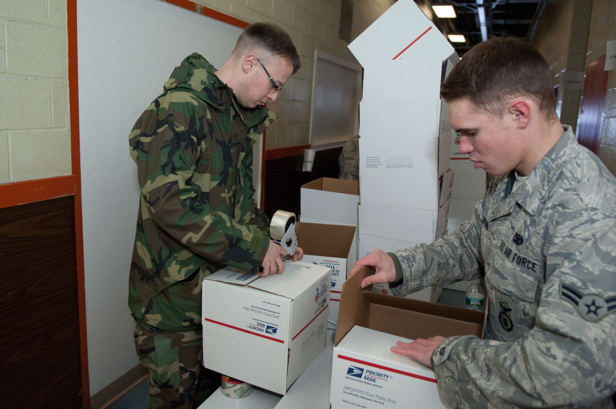 HANSCOM AIR FORCE BASE, Mass. – Staff Sgt. Anthony Balester (left) and Airman 1st Class Zachariah Radford assemble boxes at the beginning of the assembly line at the Troop Care Drive on Jan. 20. Eighty-five volunteers from across the base assembled 581 boxes during the event. (U.S. Air Force photo by Rick Berry)