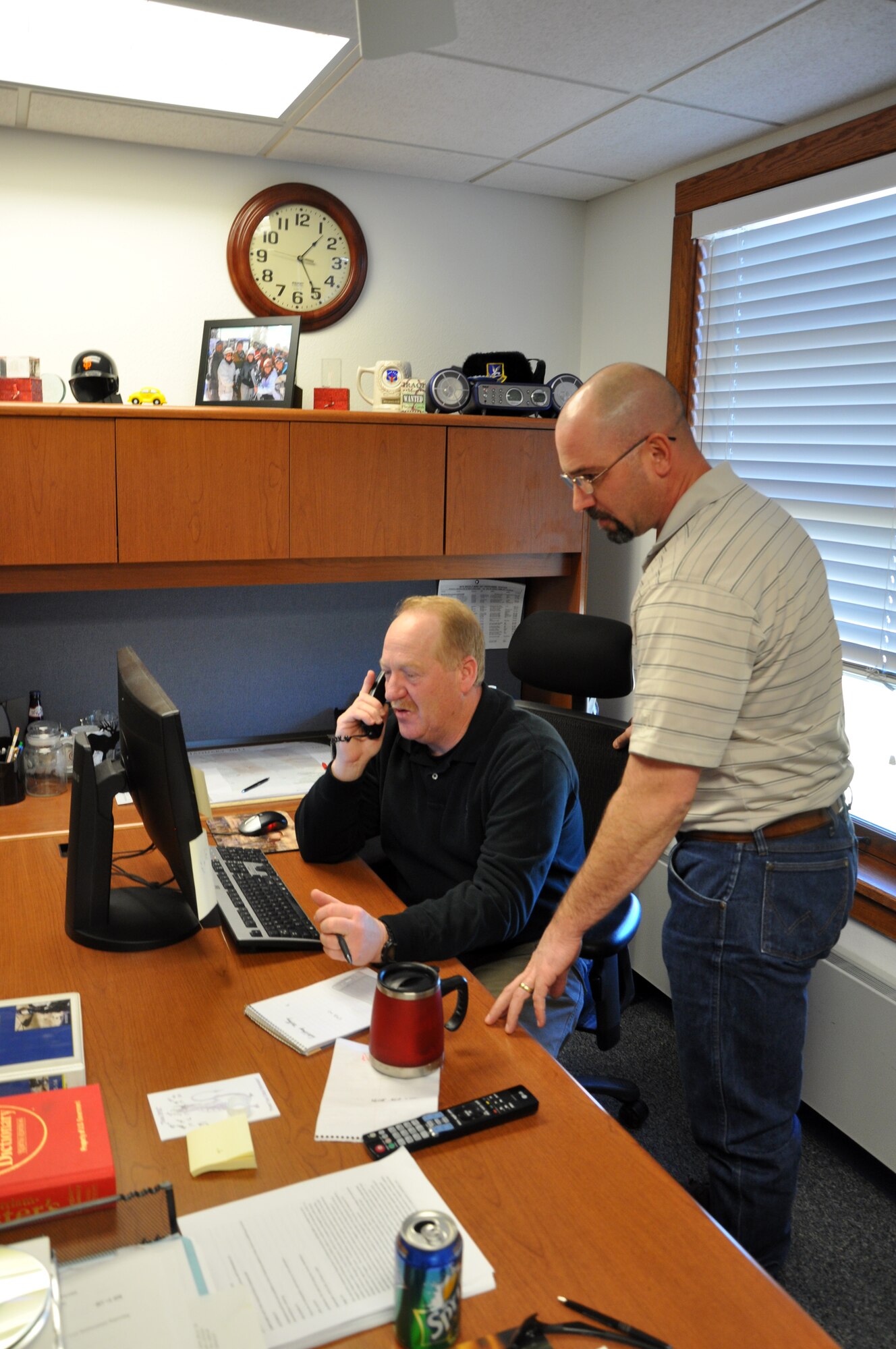 Mark Ragsdale and Kelly Young, both with the 90th Missile Wing Antiterrorism office, look over information in their office here, Jan. 26.  Mr. Ragsdale first arrived at F. E. Warren in 1993 as a security forces member, and returned to work as an AT civilian in 2005.  Mr. Young also arrived here in 2000 as a SF member, and started working in the AT program as a civilian in 2009. (U.S. Air Force photo by 1st Lt. Brooke Brzozowske)