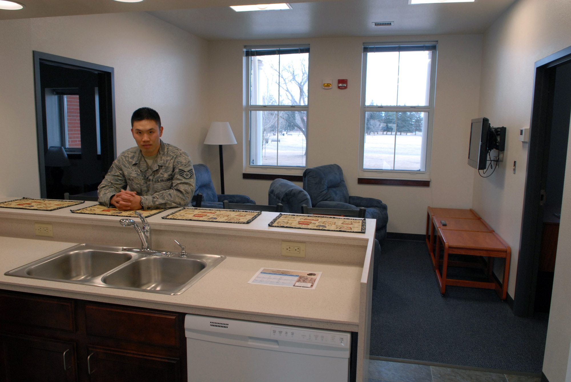 Staff Sgt. Minh Tran, 90th Civil Engineer Squadron, dormitory manager, stands in the common area of a suite in the recently remodeled Dormitory 236 Jan. 25. The suites’ common areas has a full kitchen with dishwasher, living area with a flat screen TV along with reclining chairs and a laundry area with washer and dryer. Each suite has four bedrooms, with cable hook-ups and private baths. (U.S. Air Force photo by R.J. Oriez)