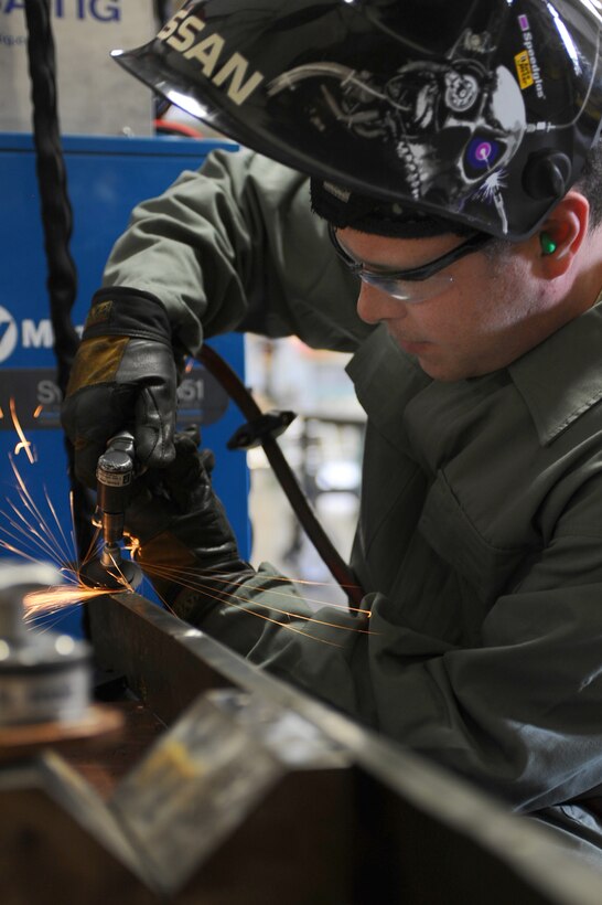 Airman 1st Class Webb Travis, 28th Maintenance Squadron metals technology technician, prepares a bomb loader panel for drilling by smoothing out the welds at Ellsworth Air Force Base, S.D., Jan. 26, 2011. (U.S. Air Force photo/Senior Airman Kasey Close)