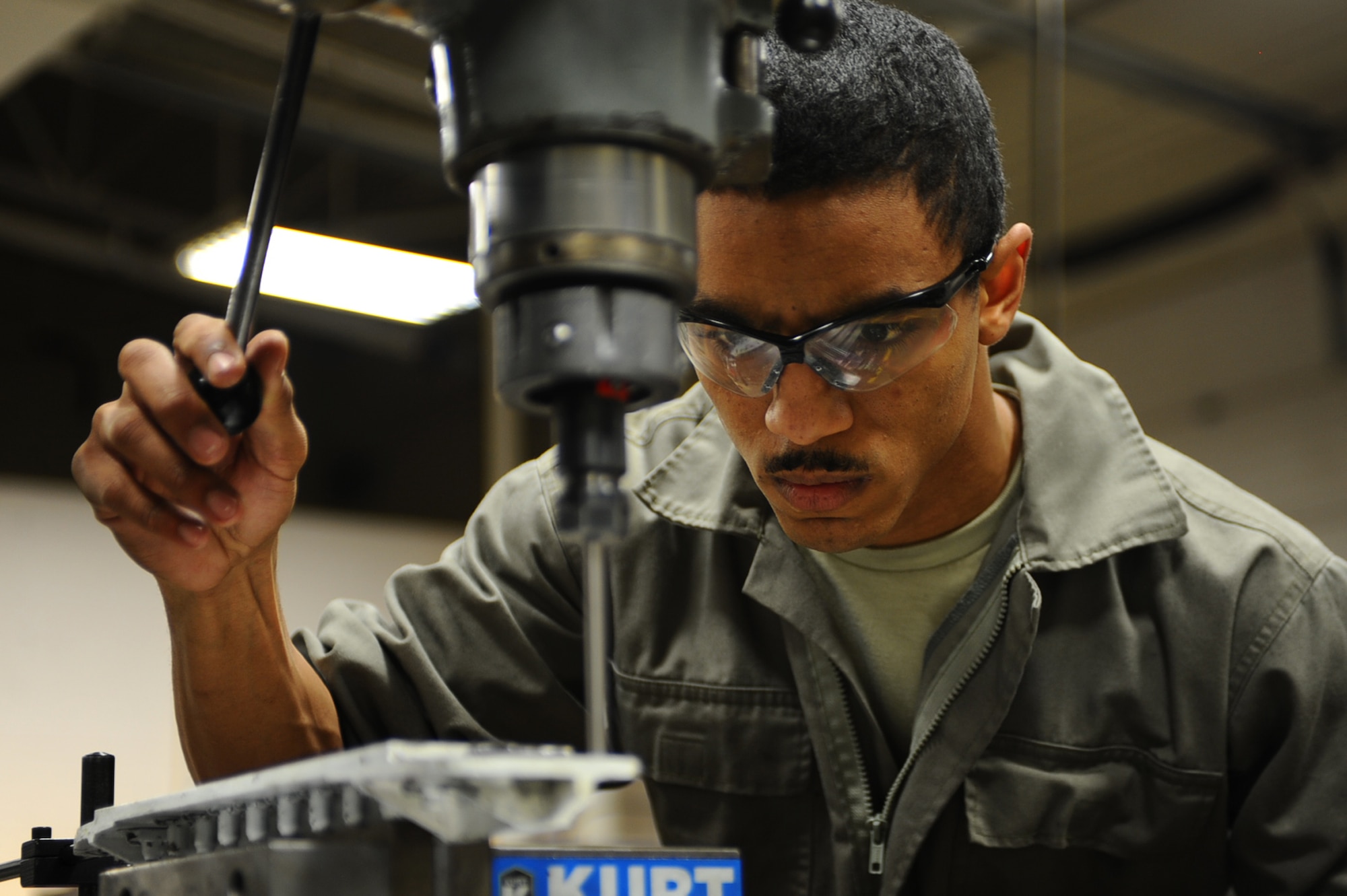 Airman 1st Class Darrell Tate, 28th Maintenance Squadron metals technology technician, positions a drill on an old fuel coolant scope bracket before milling on the replacement bracket at Ellsworth Air Force Base, S.D., Jan. 26, 2011. (U.S. Air Force photo/Senior Airman Kasey Close)