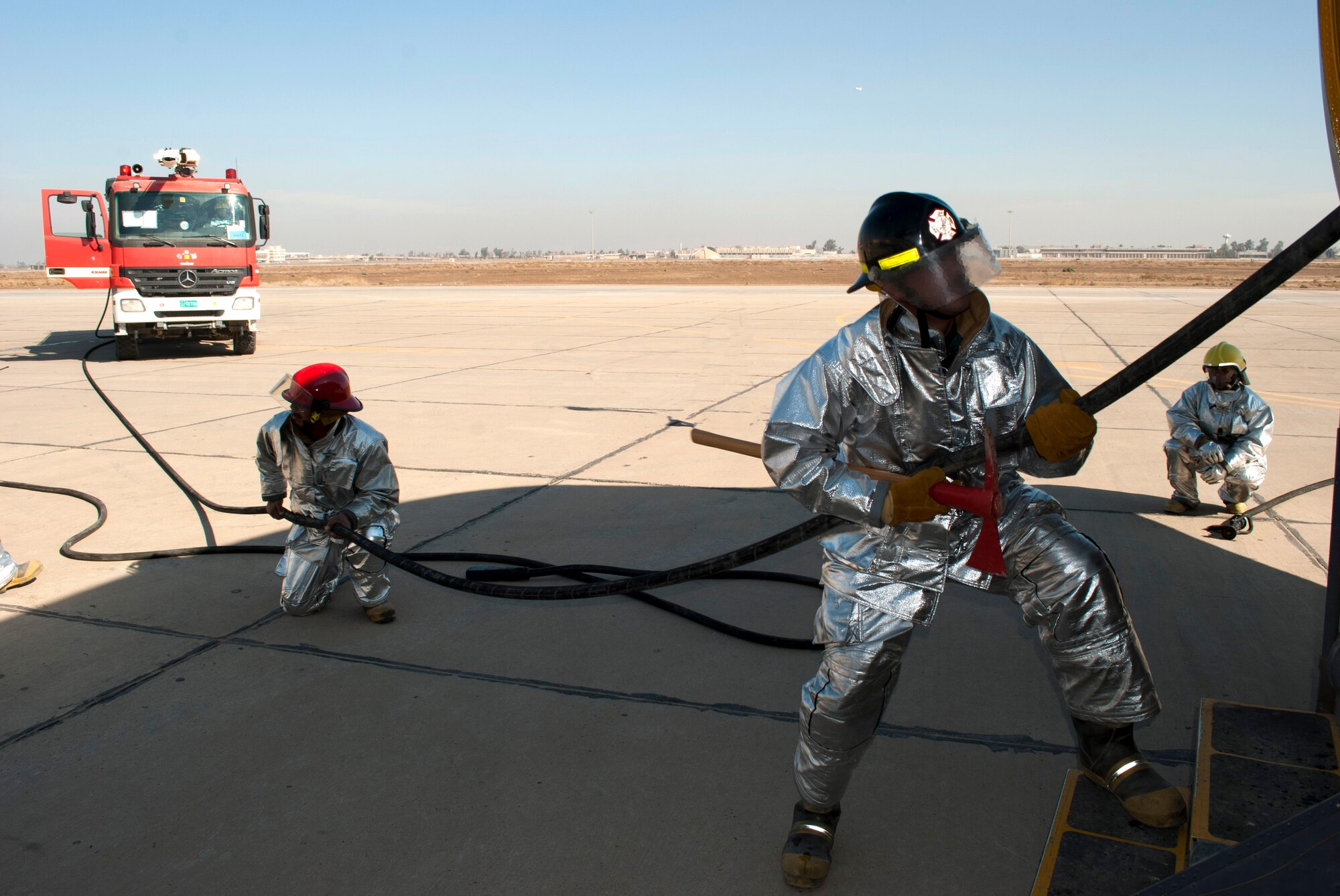 Iraqi Air Force firefighters at New Al-Muthana Air Base, Iraq, feed hose to the interior crews fighting a simulated cargo fire on a C-130 Hercules January 24.  The training was geared towards expanding IqAF firefighter knowledge and response capabilities. (U.S. Air Force photo by Tech. Sgt. Todd Barnett, released)