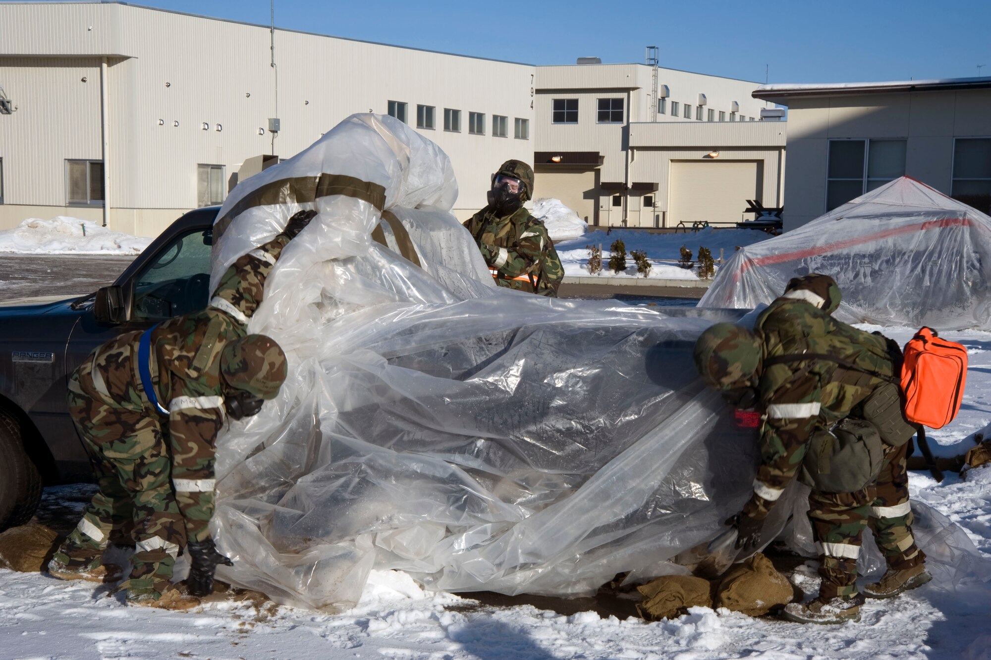 U.S. Air Force Airmen remove plastic sheeting during a decontamination drill Jan. 27, 2011, at Misawa Air Base, Japan. In a chemical or biological environment, covering equipment to protect it from contamination enhances survivability during combat operations. (U.S. Air Force photo by Tech. Sgt. Russell McBride/Released