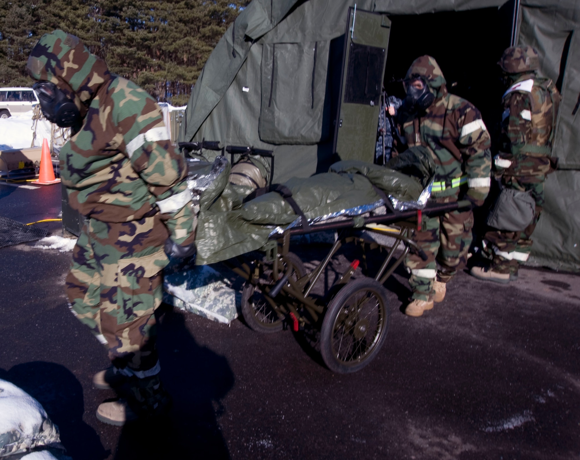 U.S Air Force medics from the 35th Medical Group move a patient from a decontamination tent during a (simulated) attack Jan. 27, 2011, at Misawa Air Base, Japan. Readiness exercises test the group?s ability to care for Airmen under a variety of conditions. Depending on the patient's injuries, they are either seen by doctors or decontaminated and returned to the fight. (U.S. Air Force photo by Tech. Sgt. Russell McBride/Released)