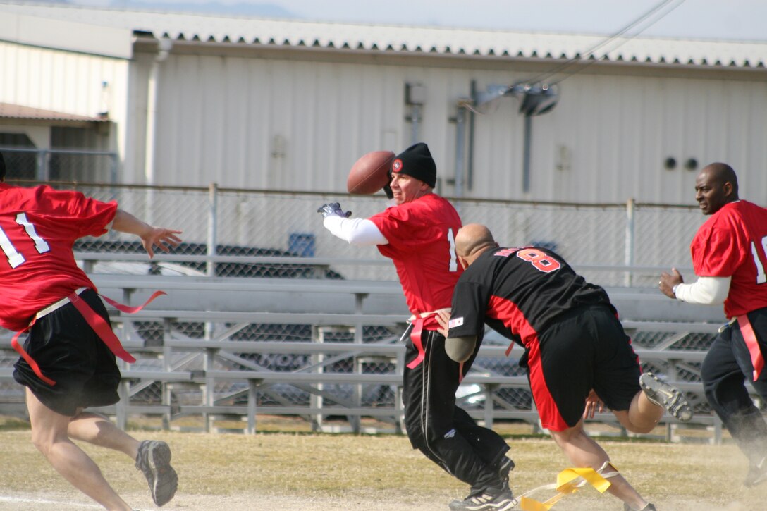 Staff Sgt. Shane Hall, O Killaz lineman, makes a grab for Lt. Col. Michael Coletta, quarterback/coach, as Coletta looks down the field for an open receiver here Jan. 28 at Penny Lake field in the Officers versus Staff Noncommissioned Officers flag football game. The SNCOs were on the losing end of a 20-13 defeat by the officers as they attempted to go for an upset.