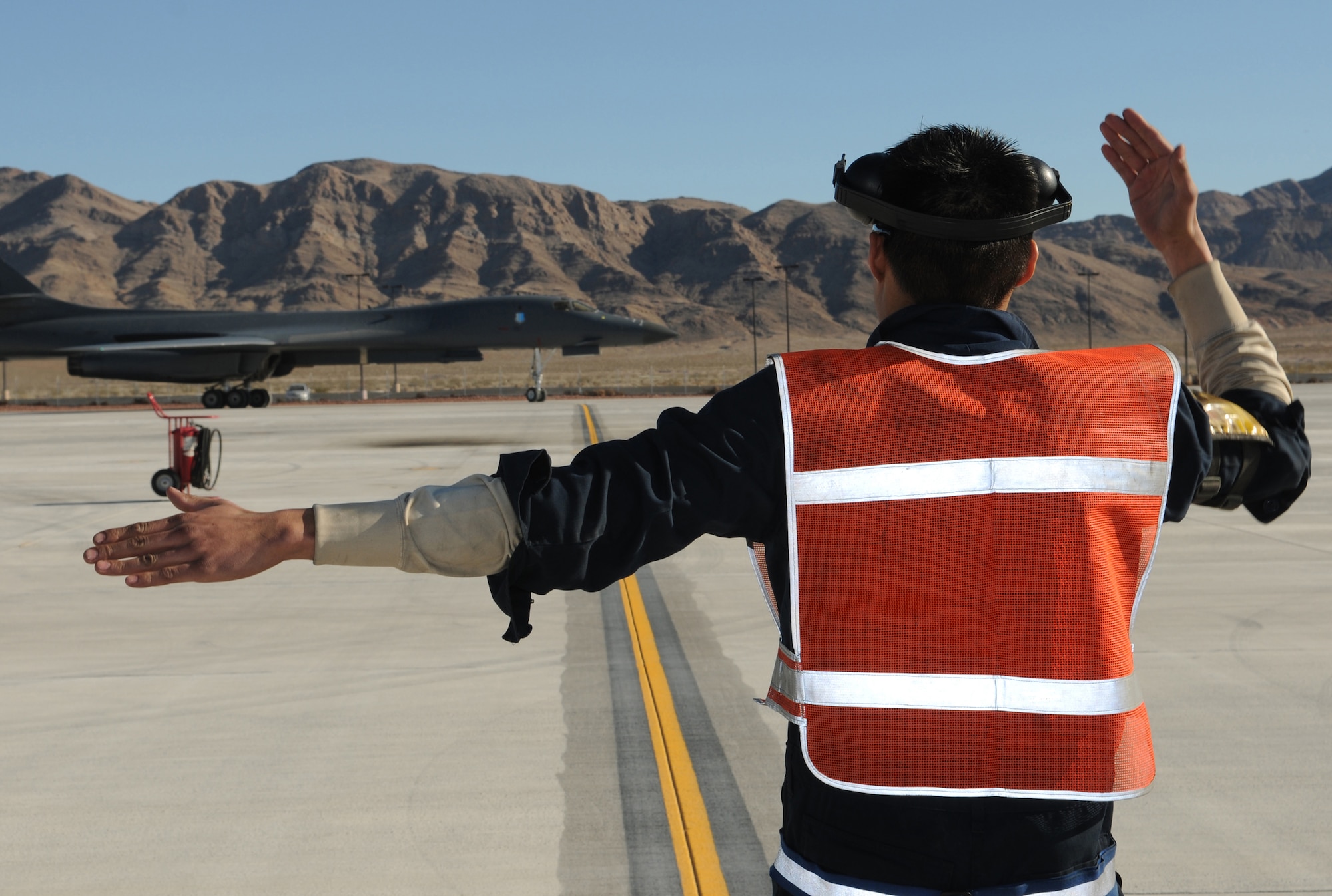 Senior Airman Kevin Faulds marshals a B-1 Lancer after a mission Jan. 26, 2011, at Nellis Air Force Base, Nev. Airman Faulds is deployed in support of Red Flag 11-2, a combined exercise that provides a realistic combat training environment to the U.S. and its allies. Airman Faulds is a 28th Aircraft Maintenance Squadron crew chief. (U.S. Air Force photo/Staff Sgt. Benjamin Wilson)