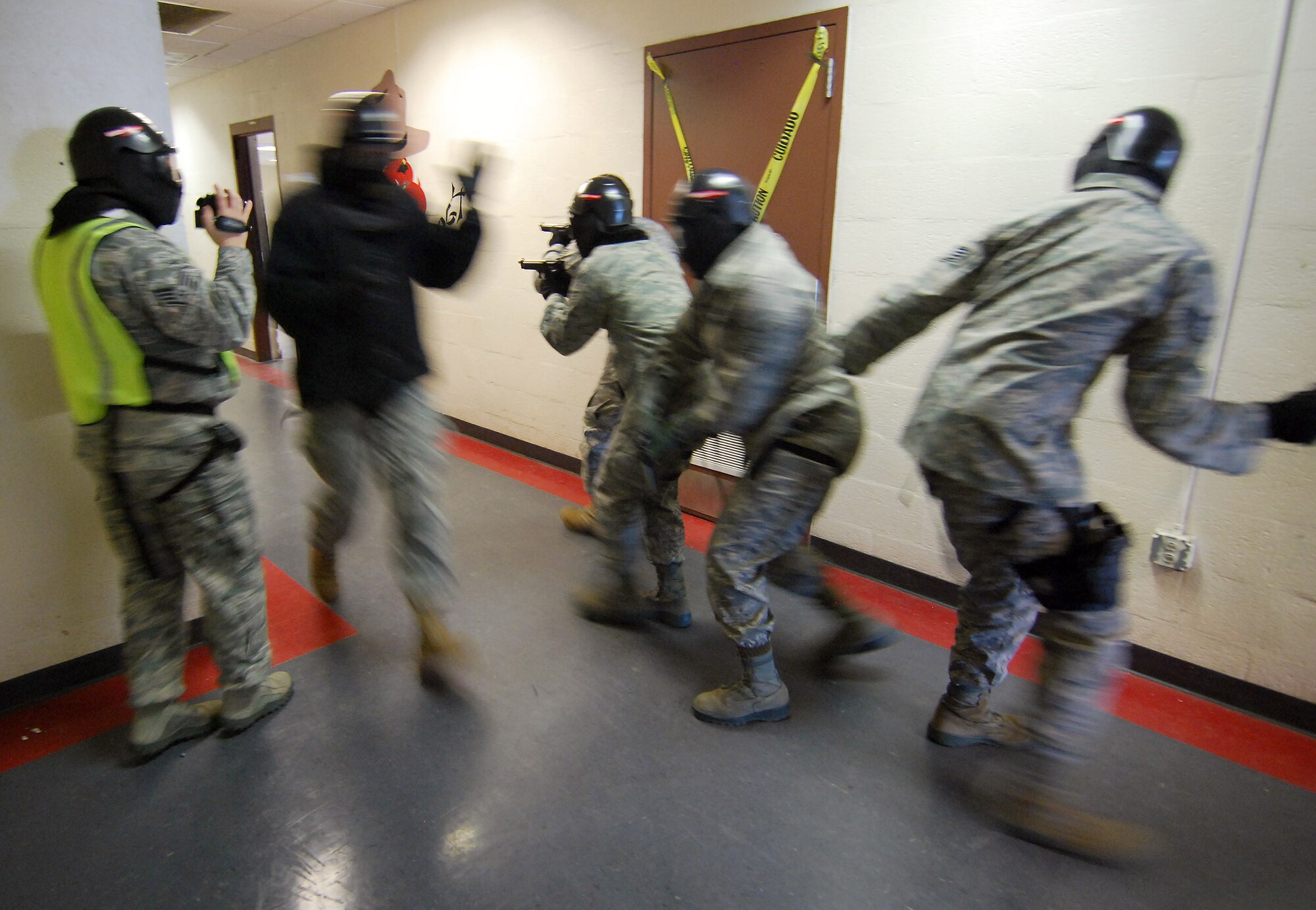 One of the "shooters" in this scenario poses as a victim and runs by a 4-person response team advancing in a tactical formation down a hallway during the Basic Active Shooter Course, Jan 27.   The training is provided by personnel from the 610th Security Forces Squadron, Joint Reserve Base Fort Worth, Texas, instructors also document every action with still and video cameras to augment the after-action review.  The team came to Dobbins Air Reserve Base to provide this critical training for the 94th Security Forces Squadron and other Dobbins area security personnel.  The two day course provides classroom and tactical instruction to first responders covering several shooting spree scenarios.  Yes, the shooter was put down by the rear guard member.   (U.S. Air Force photo/ Brad Fallin)