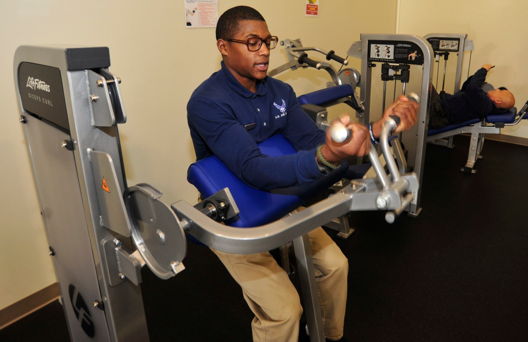 Airman 1st Class Jordan Webber, 627th Force Support Squadron fitness specialist and fitness Airman of the quarter, demonstrates the use of muscle building equipment at the McChord Field Fitness Annex Jan. 26 at Joint Base Lewis-McChord, Wash. Airmen assigned to the fitness center are required to have extensive knowledge of all equipment in order to assist customers. (U.S. Air Force photo/Airman Leah Young)