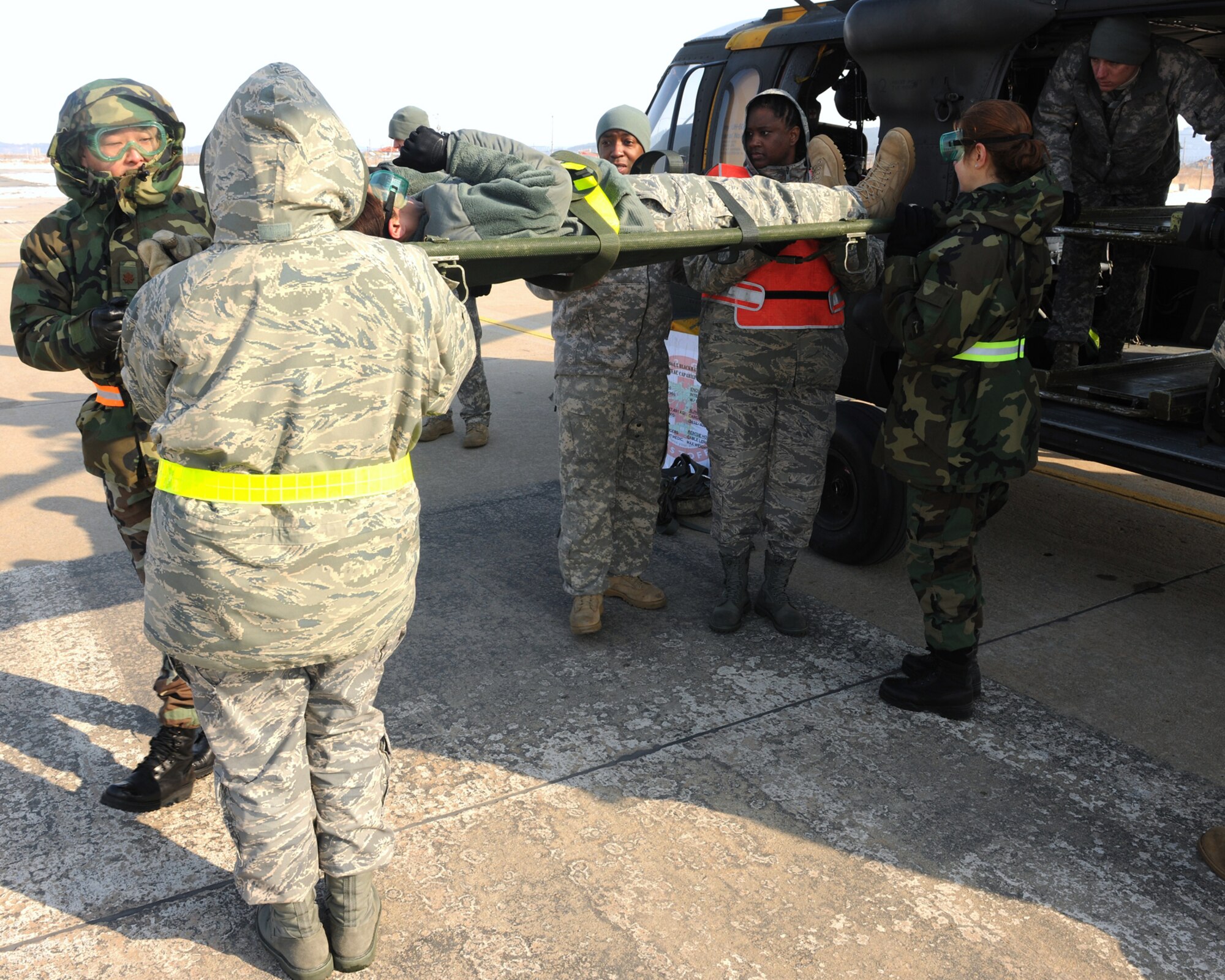 Members of the 8th Medical Group load a litter onto a UH-60 Black Hawk as Army Staff Sgt. Reginald Jones, a UH-60 flight medic, observes during medical evacuation training Jan. 19, 2011, at Kunsan Air Base, South Korea. (U.S. Air Force photo/Senior Airman Ciara Wymbs) 