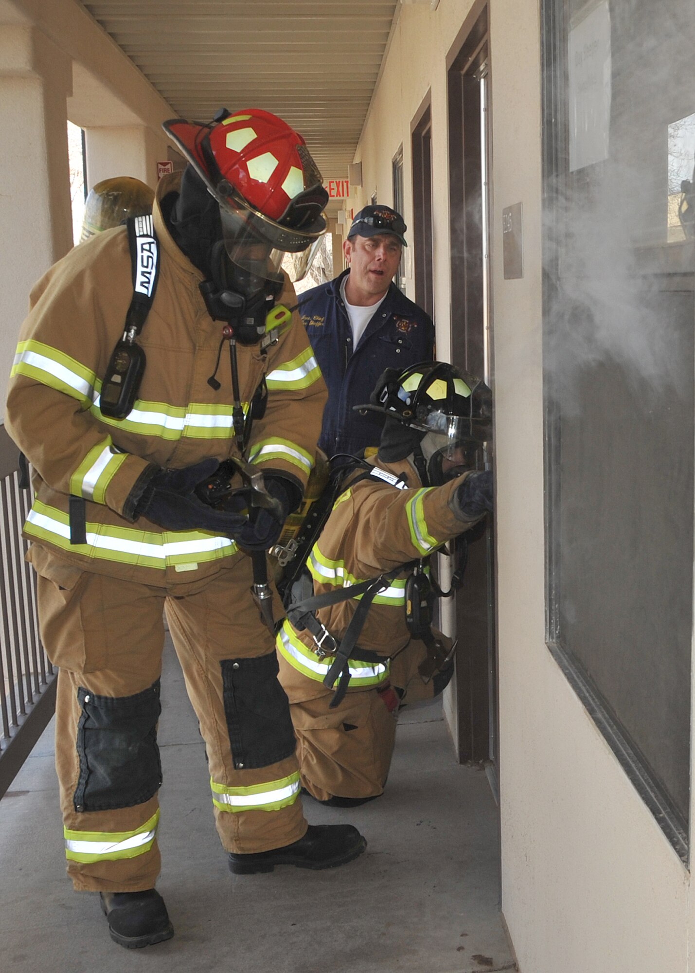 Kirtland Air Force Base firefighters evaluate a dorm room as smoke billows from the window Jan. 25 during an operational readiness exercise.  Fire department evaluator Lee Schaffer, center, observes the firefighters during the exercise.  
Team Kirtland participated in an exercise Jan. 24 to 28 in preparation for the Operational Readiness Inspection in March.
The exercise included various elements to prepare units for the upcoming ORI.
U.S. Air Force Photo by Todd Berenger