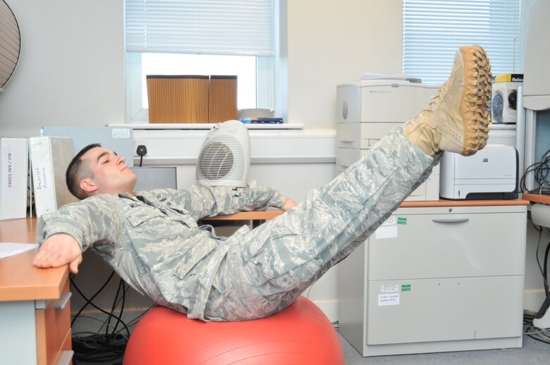 ROYAL AIR FORCE LAKENHEATH, England - Senior Airman Jared McGrady, 48th Force Support Squadron fitness and sports specialist, demonstrates a leg lift at his office, Jan. 18. Exercises such as this, using a stability ball that can be easily stored under a desk, are quick and easy ways to squeeze fitness into a busy work day. (U.S. Air Force photo/Senior Airman David Dobrydney)