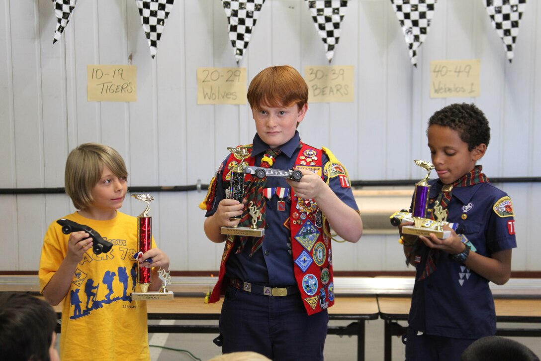 First, second and third place finishers display their cars and their trophies to the audience during the Cub Scouts’ Pinewood Derby at the Combat Center’s Scout Hut Jan 29, 2011.