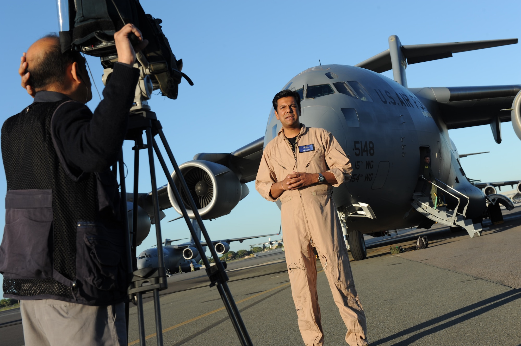 Ajmal Jami, a cameraman with New Delhi Television station, records Vishnu Som, senior news anchor with NDTV, as he speaks about the C-17s on the 15th Wing flightline Jan. 25. The NDTV crew flew aboard a C-17 and documented the capabilities of the aircraft on a routine training mission to Kona, Hawaii. (U.S. Air Force photo/Airman 1st Class Lauren Main)