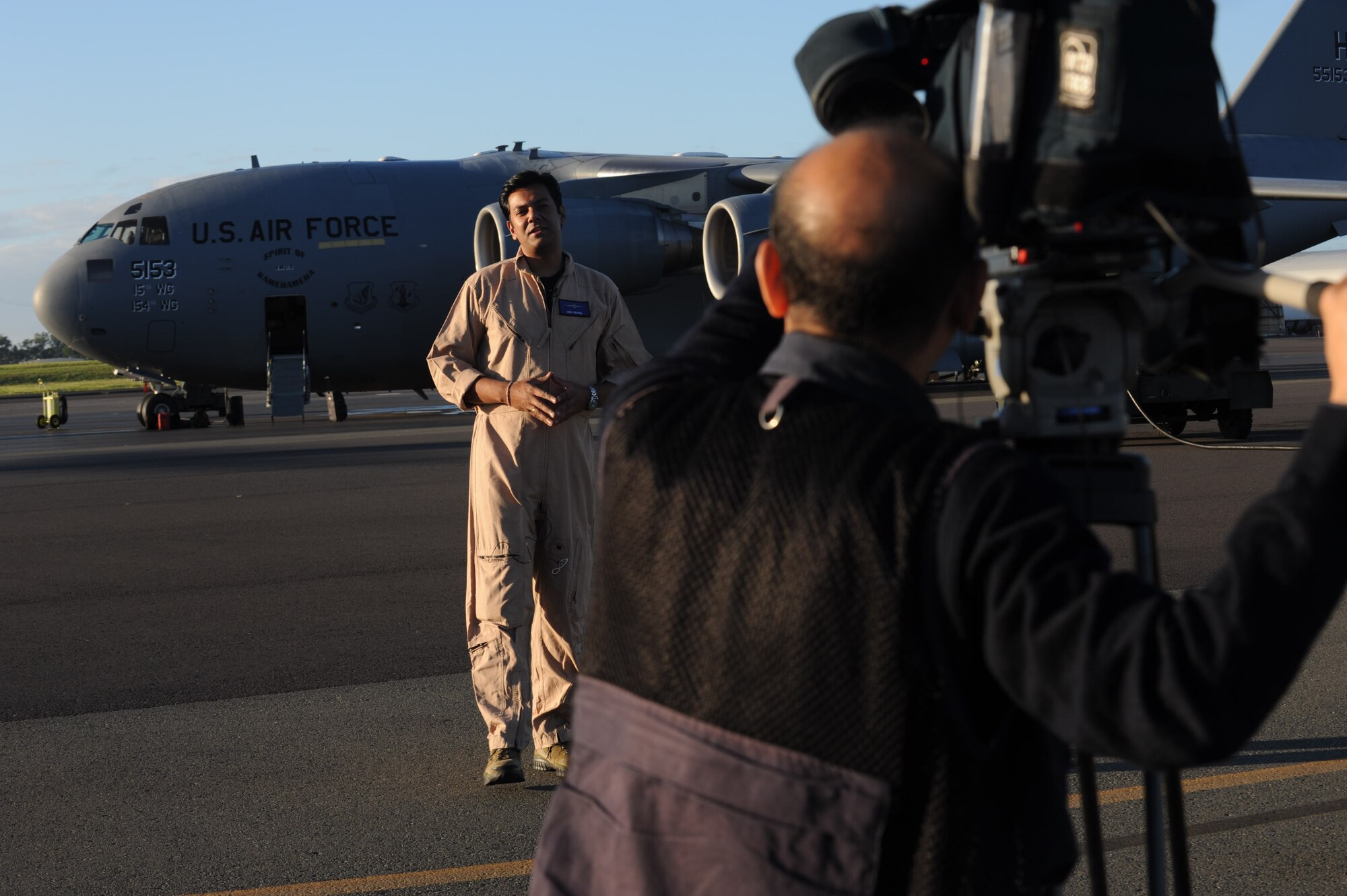 Ajmal Jami, a cameraman with New Delhi Television station, records Vishnu Som, senior news anchor with NDTV, as he speaks about the C-17s on the 15th Wing flightline Jan. 25. The NDTV crew flew aboard a C-17 and documented the capabilities of the aircraft on a routine training mission to Kona, Hawaii. (U.S. Air Force photo/Airman 1st Class Lauren Main)