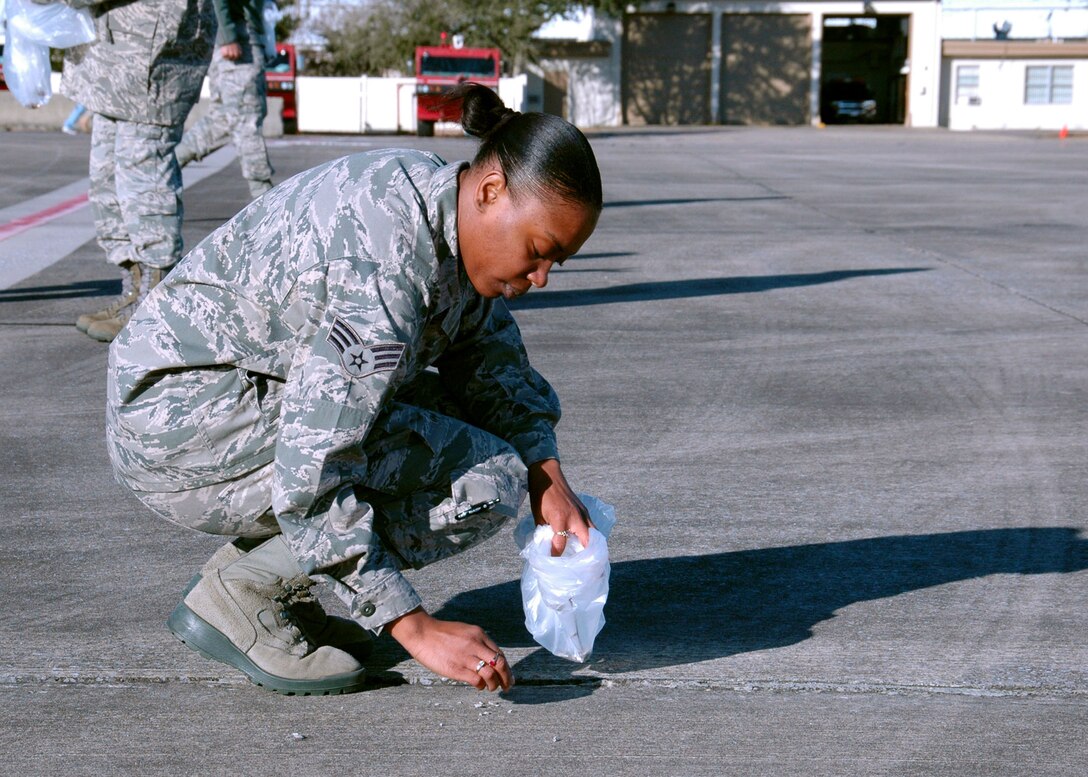On the Duke Field flightline, Senior Airman Natassa Evans, 919th Force Support Squadron, finds and removes foreign objects Jan. 27 that could potentially damage operating aircraft .  The wing commander called on volunteers to help prepare the tarmac for the return of its aircraft temporarily stationed at nearby Eglin Air Force Base, Fla., during an eight-month airfield construction project.  (U.S. Air Force photo/Adam Duckworth)