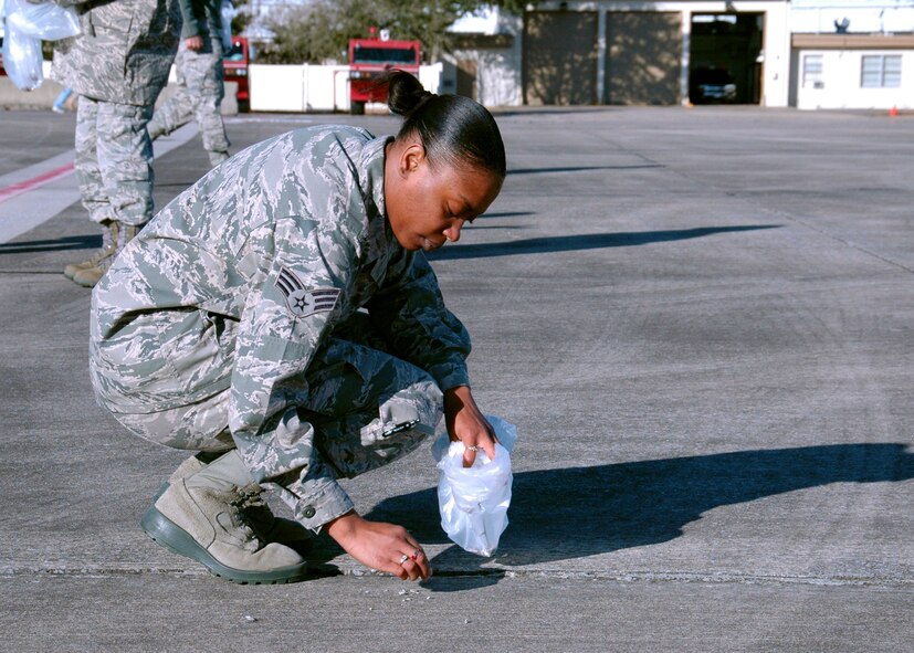 On the Duke Field flightline, Senior Airman Natassa Evans, 919th Force Support Squadron, finds and removes foreign objects Jan. 27 that could potentially damage operating aircraft .  The wing commander called on volunteers to help prepare the tarmac for the return of its aircraft temporarily stationed at nearby Eglin Air Force Base, Fla., during an eight-month airfield construction project.  (U.S. Air Force photo/Adam Duckworth)