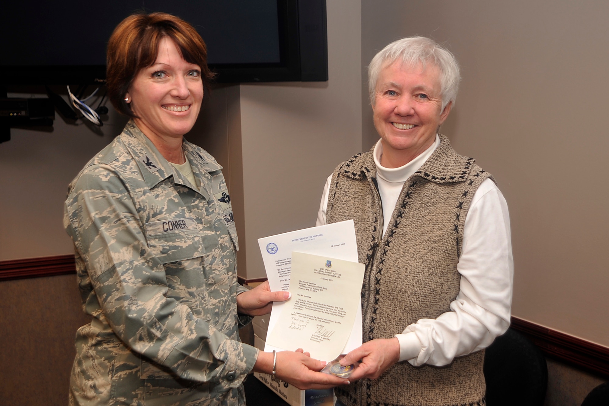PETERSON AIR FORCE BASE, Colo. – Col. Kimerlee Conner, 21st Mission Support Group commander, presents Bev Jennings, Peterson AFB Thrift Shop manager, with a letter of appreciation and a coin from Col. Stephen N. Whiting, 21st Space Wing commander, on Jan. 25, for outstanding volunteer service on Peterson AFB for 20 years. (U.S. Air Force photo/Dennis Howk)