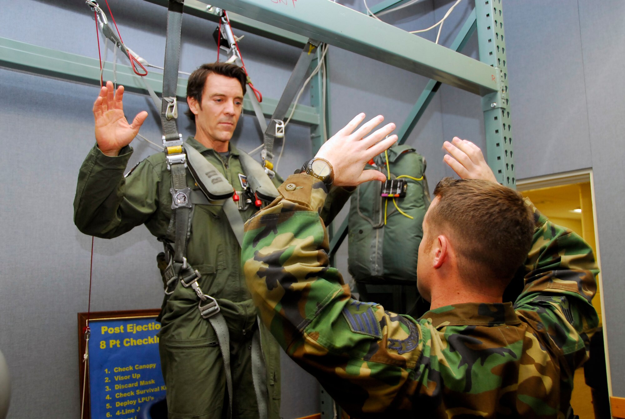 Staff Sgt. Robert Colliton, 18th Operations Support Squadron survival, evasion, resistance, escape (SERE) specialist, trains Tony Horton, creator of the fitness program, P90X, on proper parachuting techniques before his F-15 incentive flight, Jan. 29. Mr. Horton visited Kadena to put on an extreme fitness clinic at the Risner Fitness Center earlier that morning, as part of Armed Forces Entertainment’s “Ripped and Ready Tour” to promote physical fitness for service members and their families. (U.S. Air Force photo/ Airman 1st Class Maeson L. Elleman)