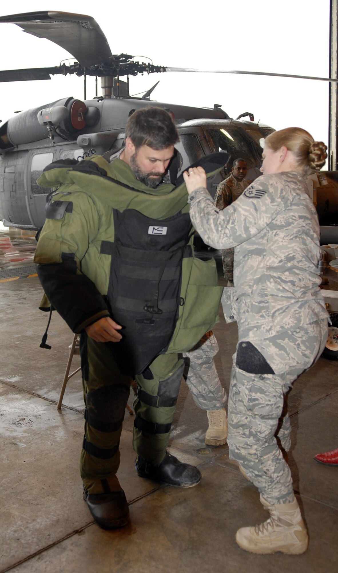 Troy Gentry, of country duo Montgomery Gentry, is helped into an explosive ordnance disposal suit by Staff Sgt. Molly Callen, an EOD journeyman, during a ‘meet and greet’ on Kadena Air Base, Japan, Jan. 28. Montgomery Gentry came to Kadena as the last stop of a USO tour. (U.S. Air Force photo/ Airman 1st Class Tara A. Williamson)